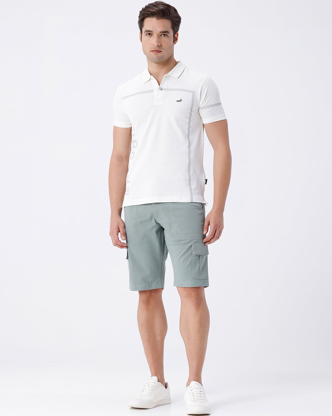 Man wearing a olive garment dyed cargo shorts in olive on a light gray background