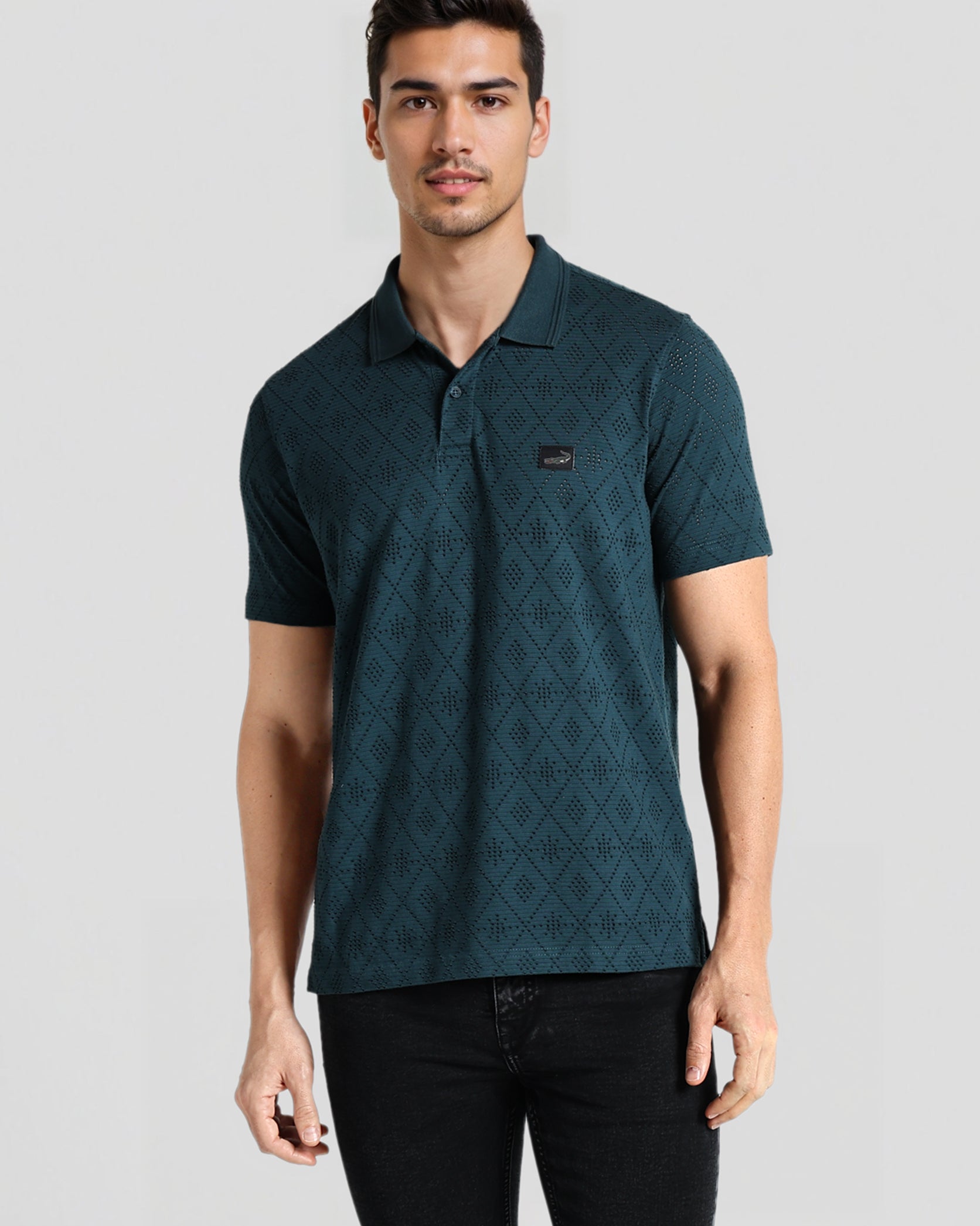 Man wearing a green patterned polo shirt on a gray background