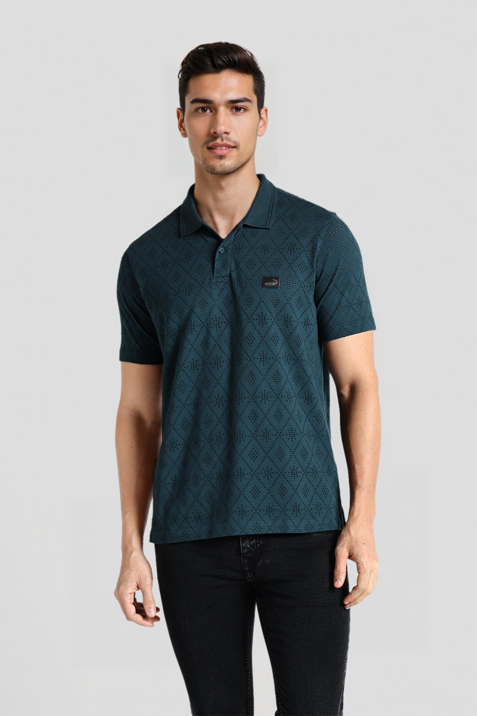 Man wearing a green patterned polo shirt on a gray background