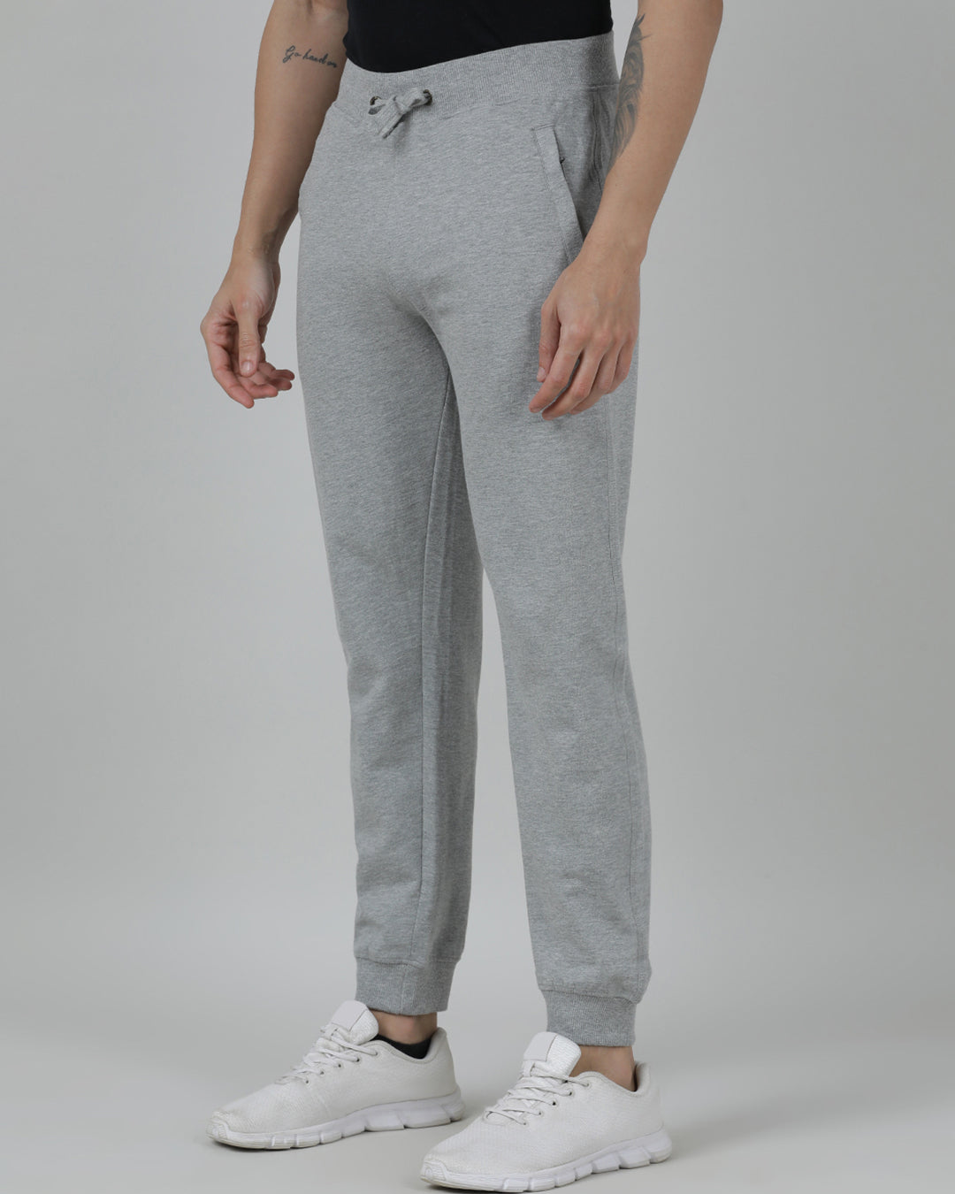 Person wearing gray sweatpants and white sneakers on a plain background