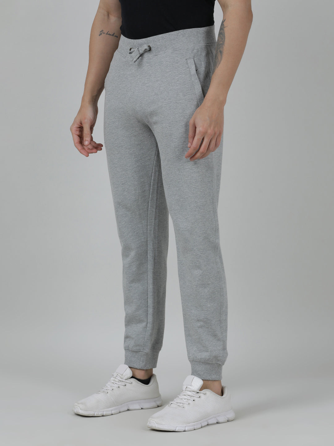 Person wearing gray sweatpants and white sneakers on a plain background