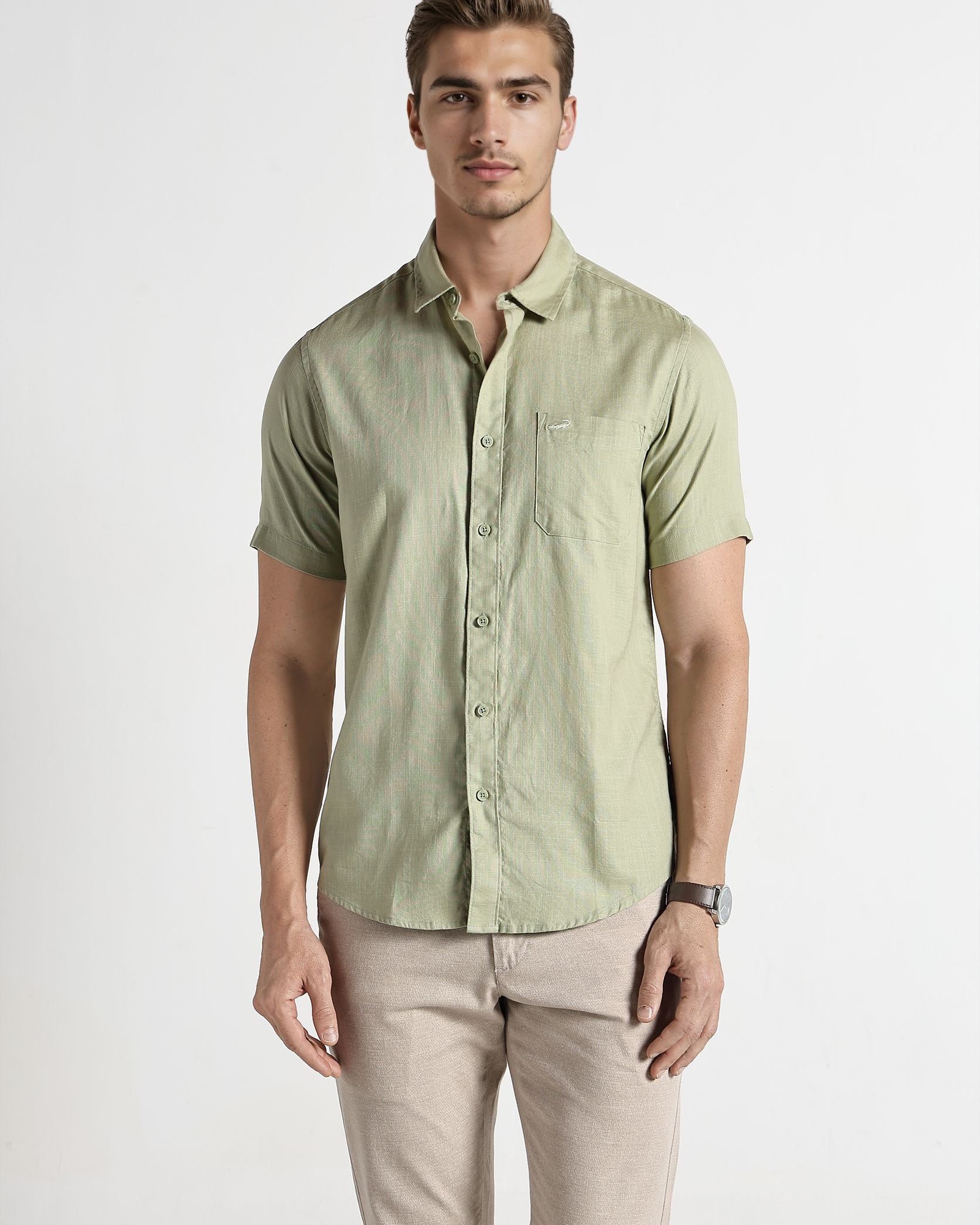 Man wearing a light green button-up shirt and beige pants on a white background