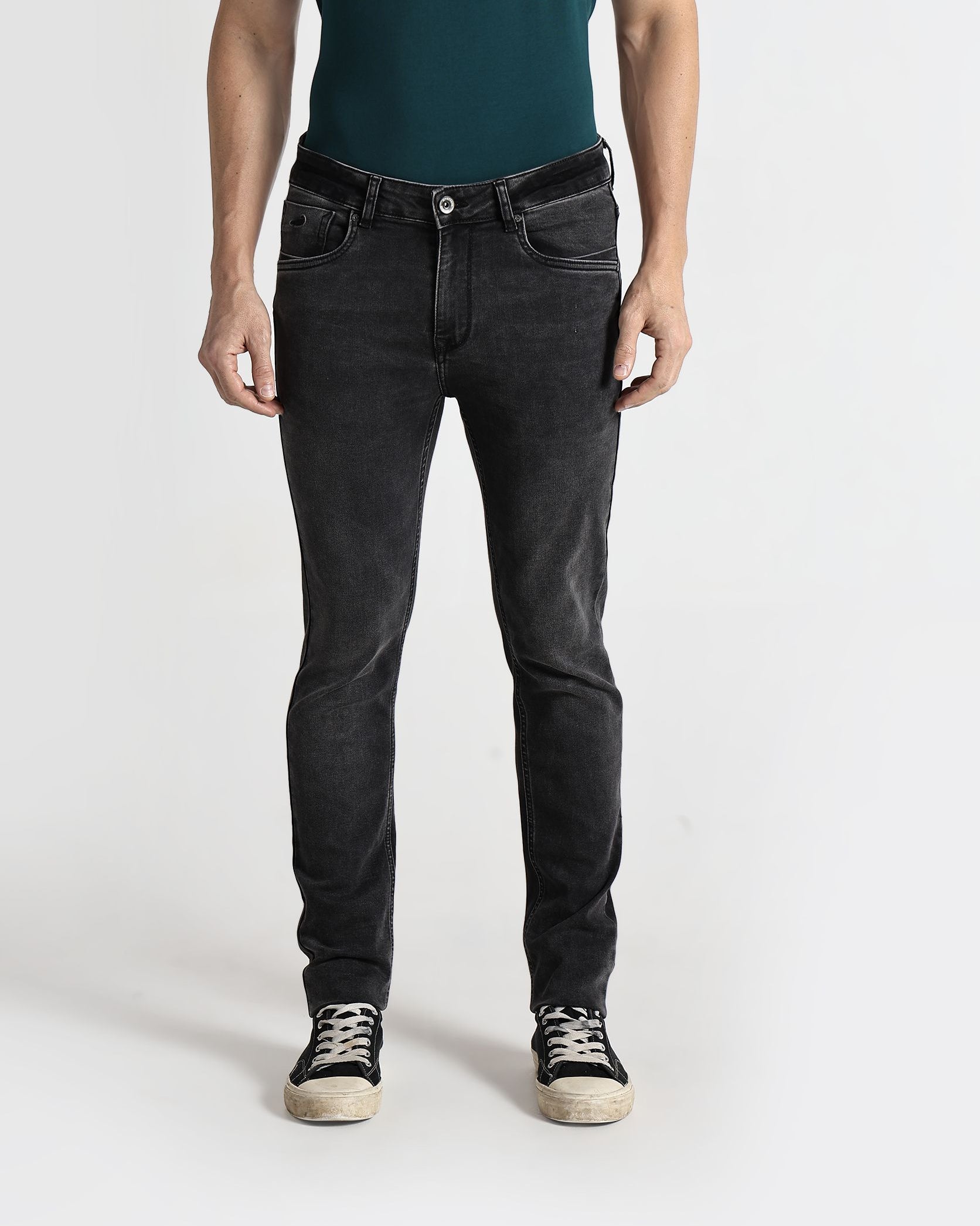 Person wearing black jeans and a green shirt on a white background