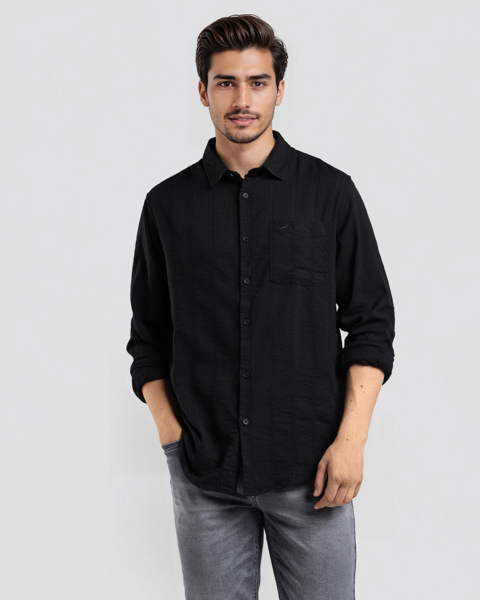 Man wearing a black shirt and gray pants against a white background