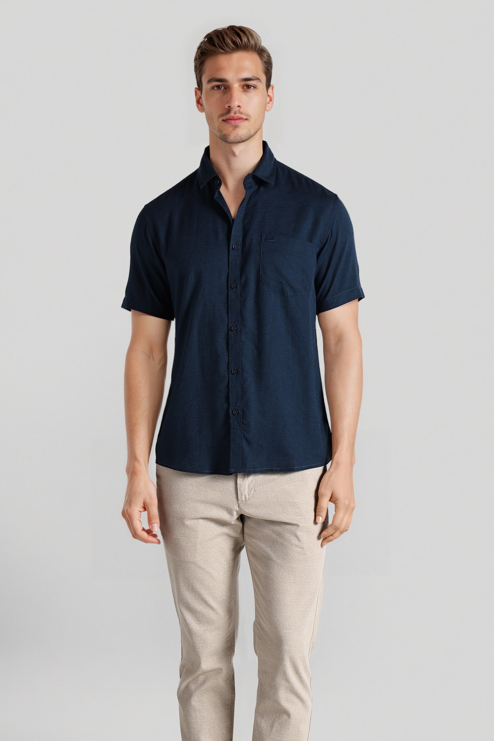 Man wearing a navy short-sleeve shirt and beige pants on a light gray background