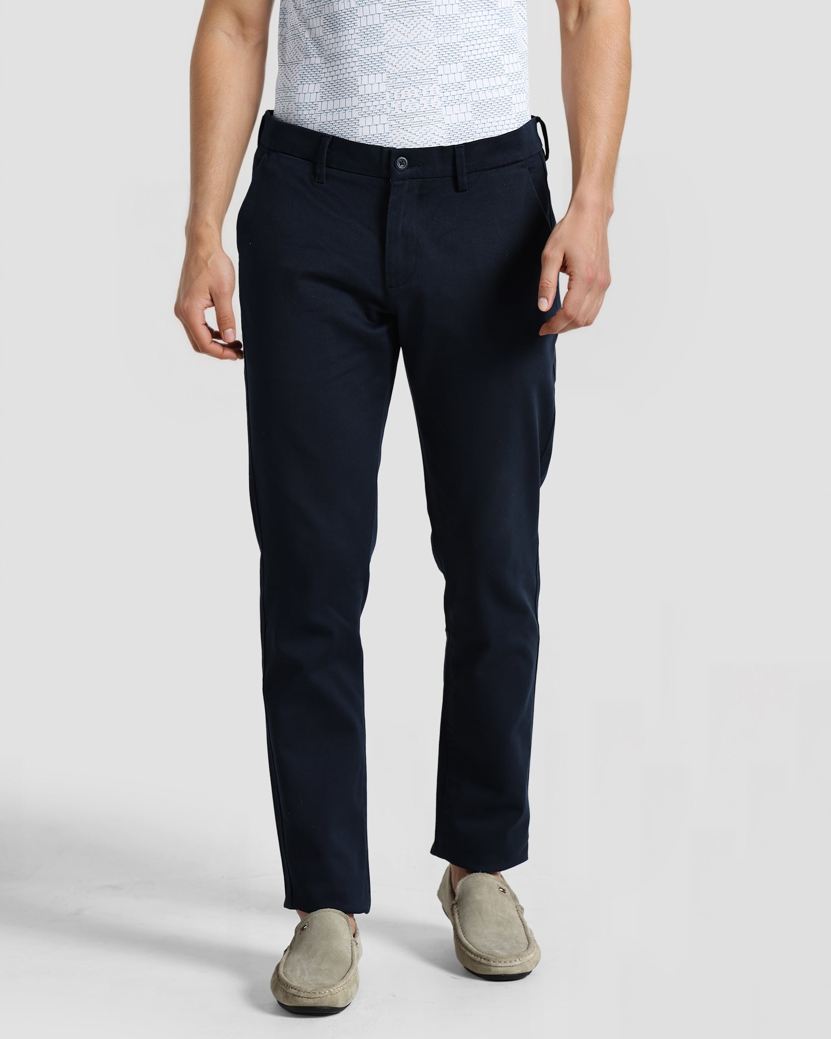 Person wearing navy pants and a gray shirt on a white background