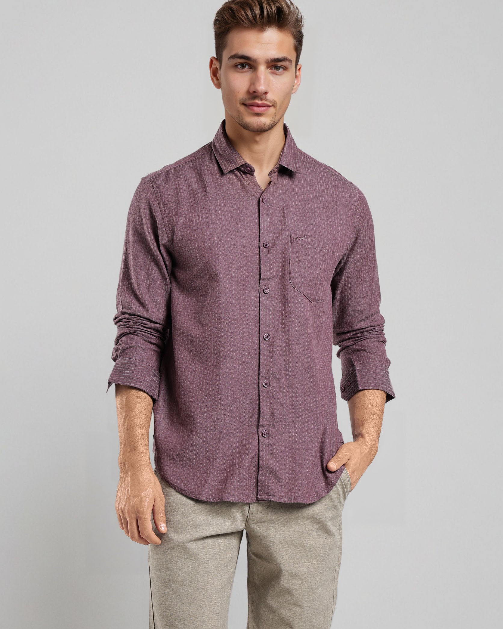 Man wearing a purple button-up shirt and beige pants against a gray background
