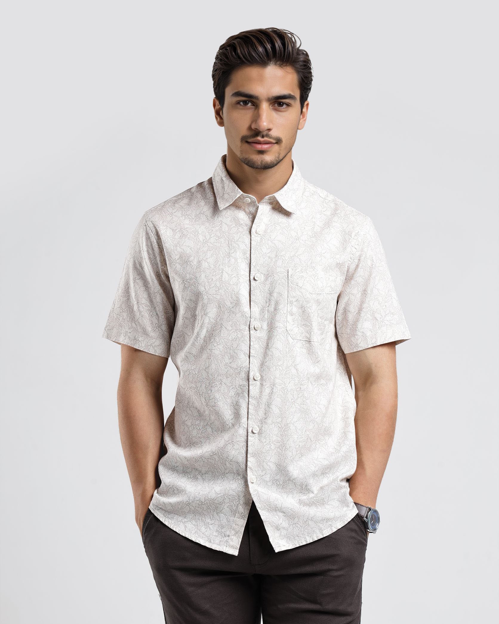 Man wearing a light-colored short-sleeve shirt and dark pants on a white background