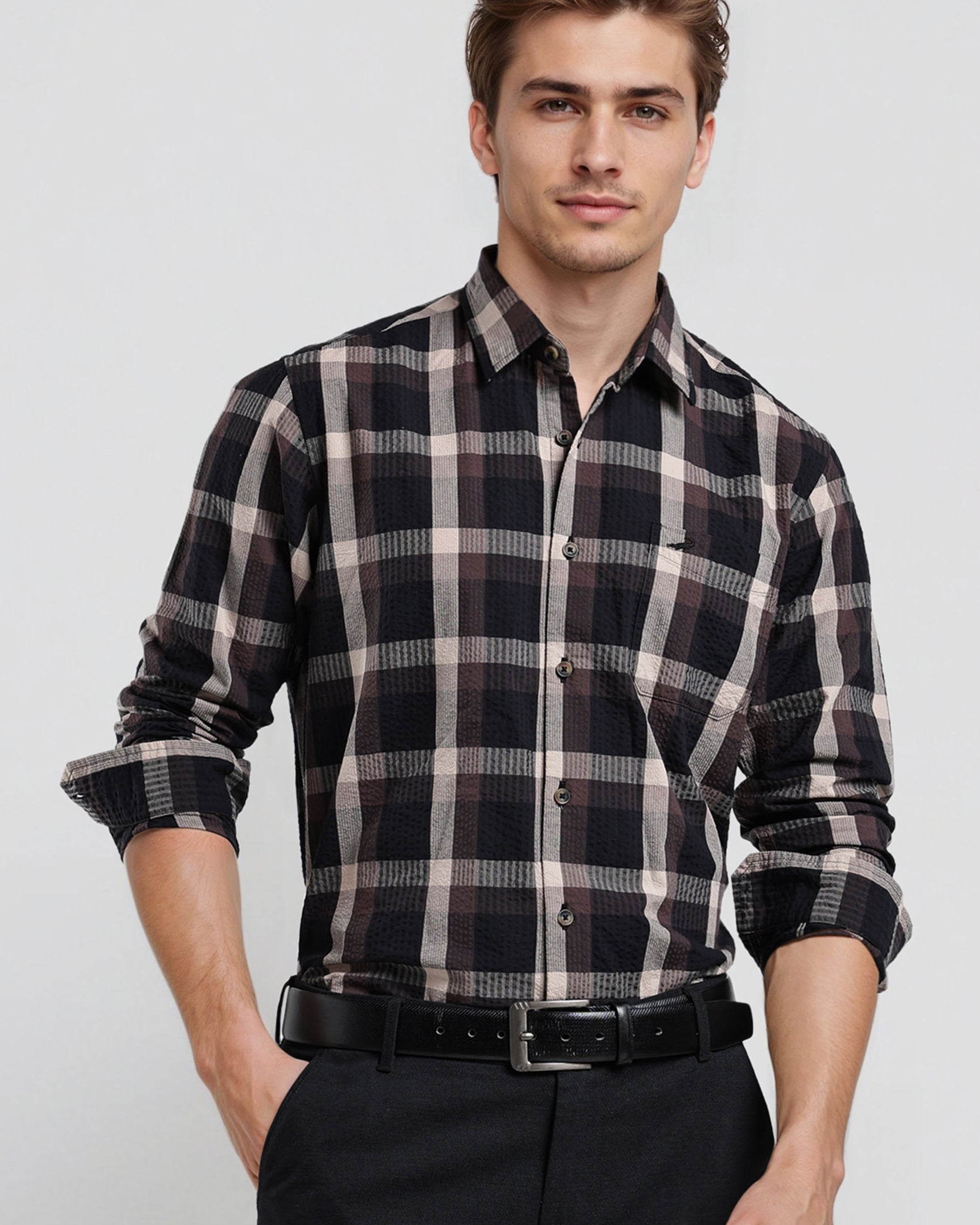 Man wearing a black and white plaid shirt with rolled-up sleeves on a white background