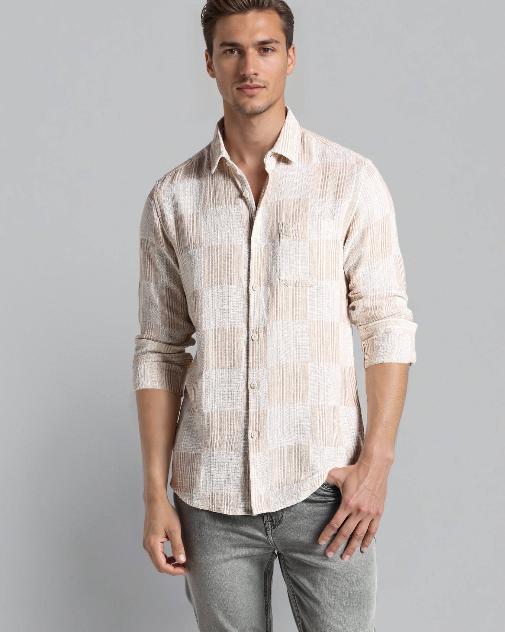 Man wearing a patterned shirt and gray pants on a gray background