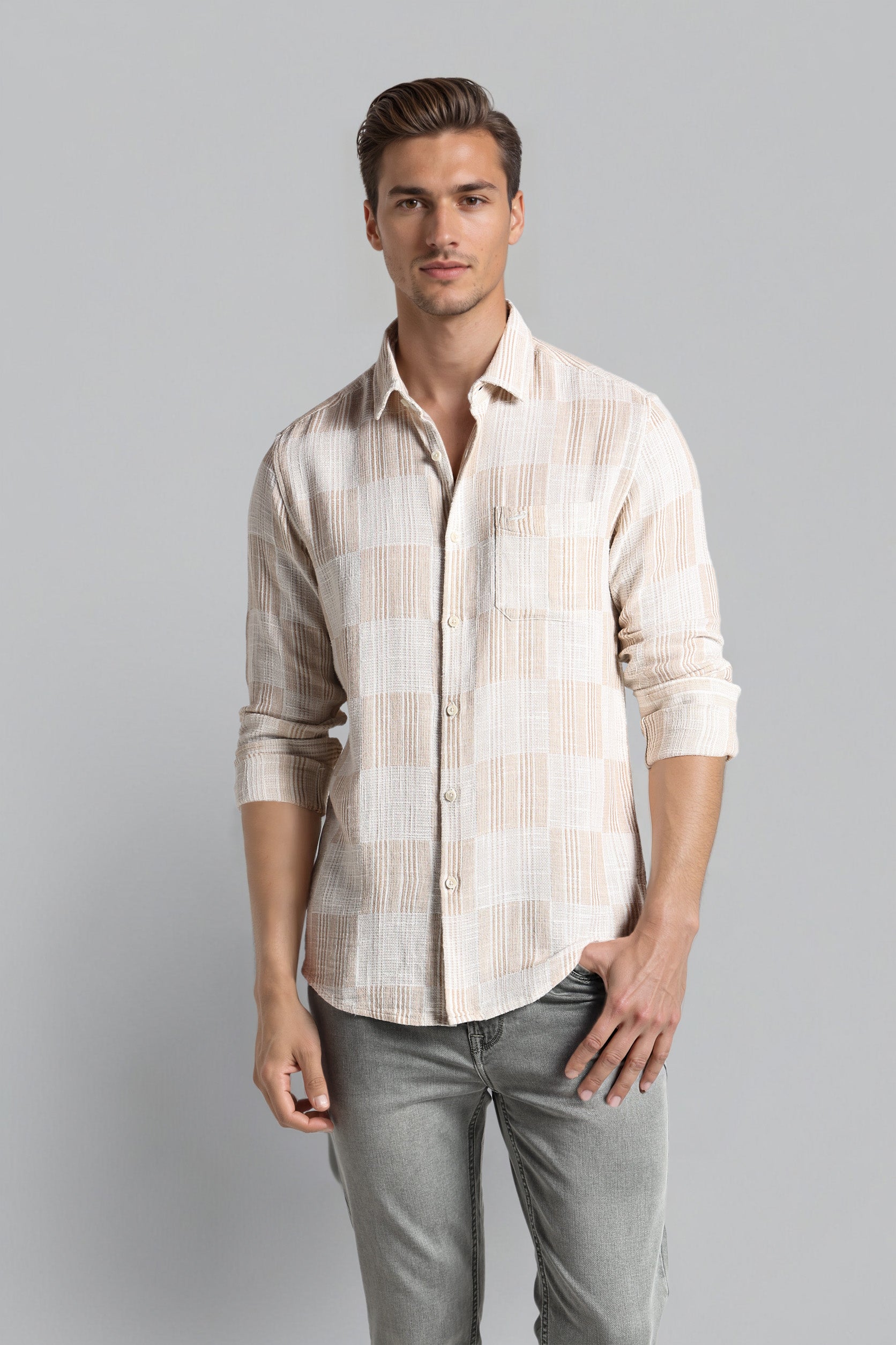 Man wearing a patterned shirt and gray pants on a gray background