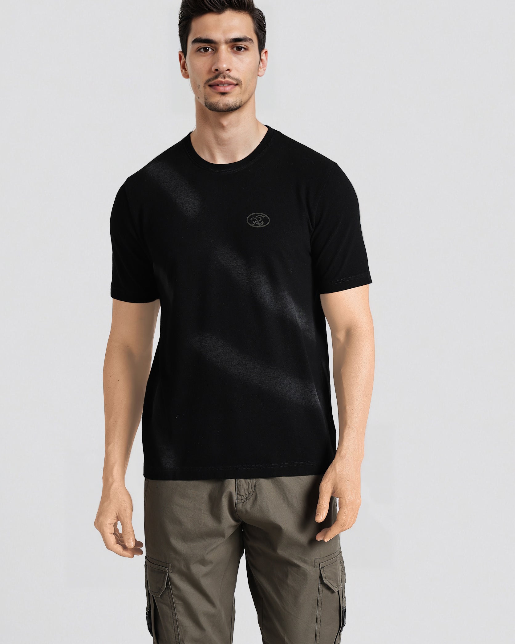 Man wearing a black t-shirt with a logo on a light gray background