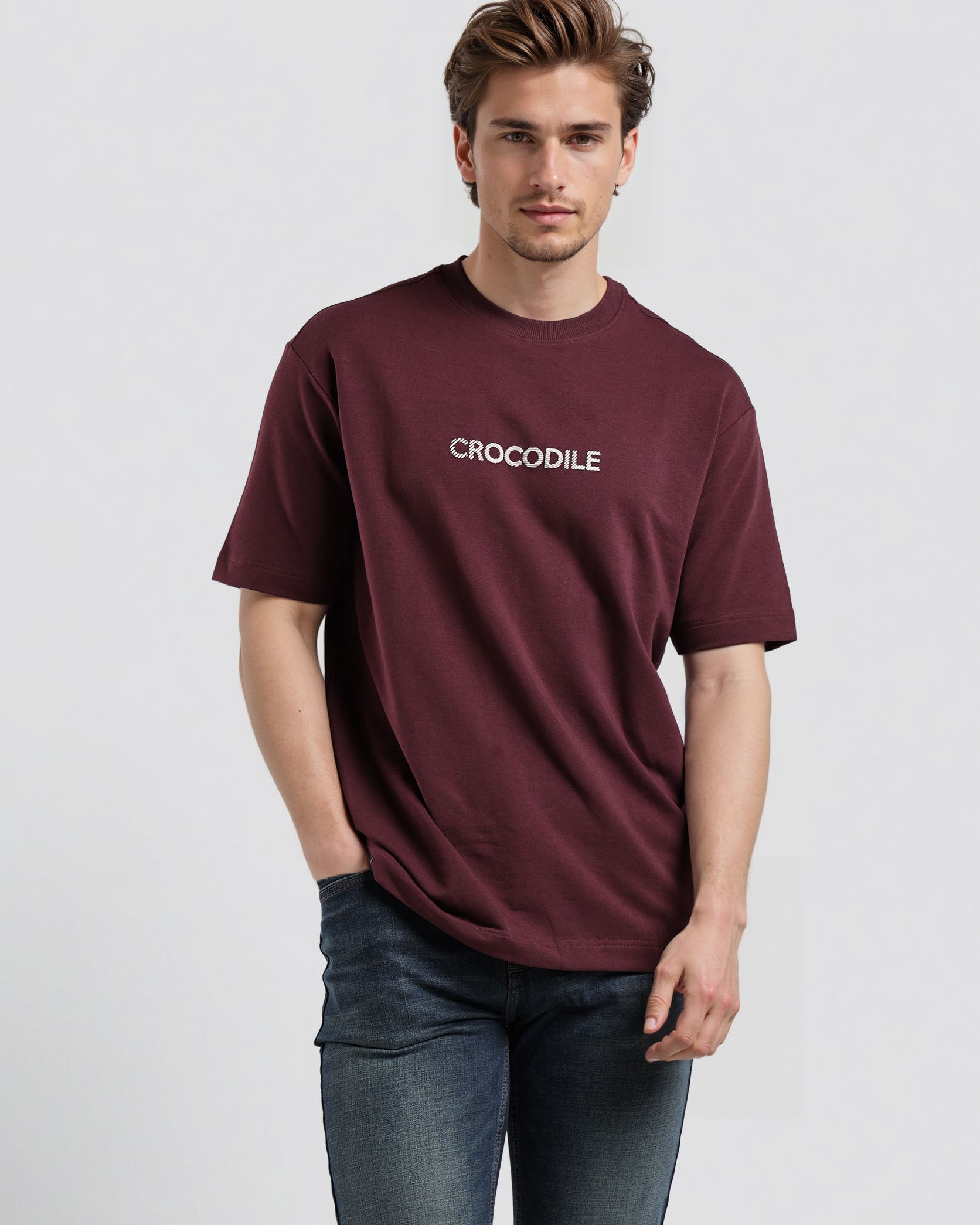 Man wearing a maroon t-shirt with a logo on a light gray background