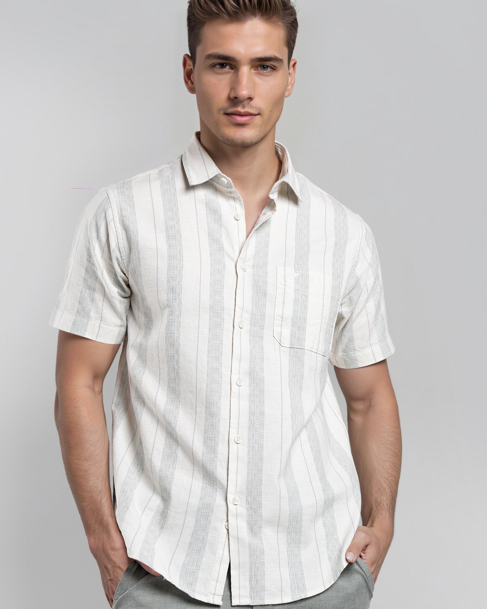 Man wearing a white striped shirt and gray pants on a gray background