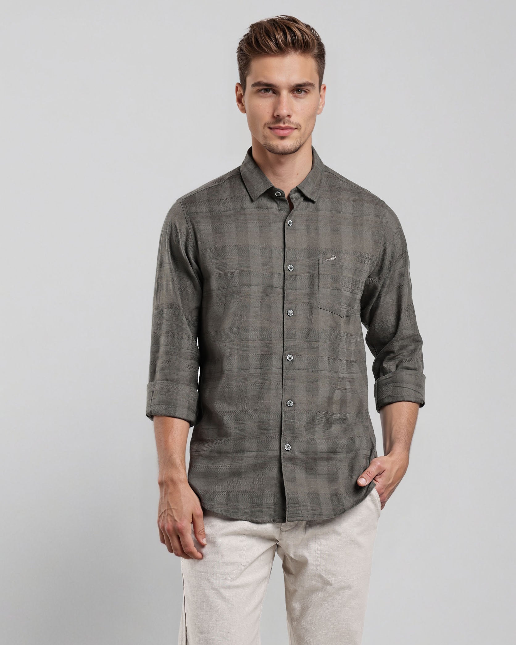 Man wearing a gray checkered shirt and white pants on a light gray background