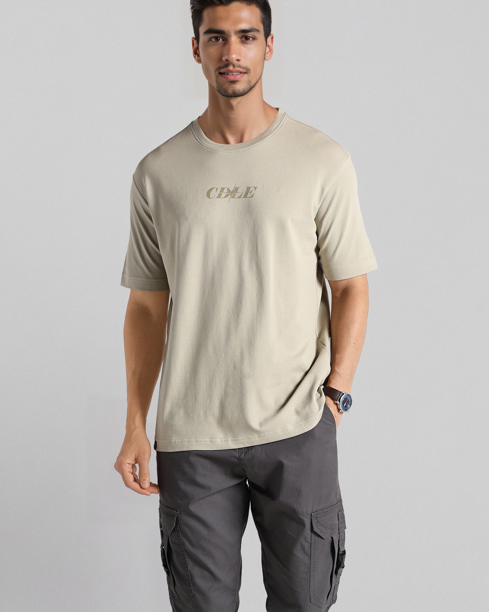 Man wearing a beige t-shirt and gray cargo pants on a light gray background
