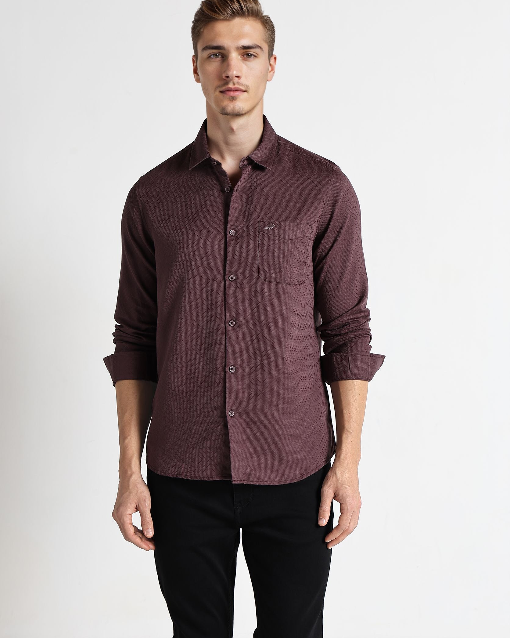 Man wearing a maroon button-up shirt and black pants on a white background