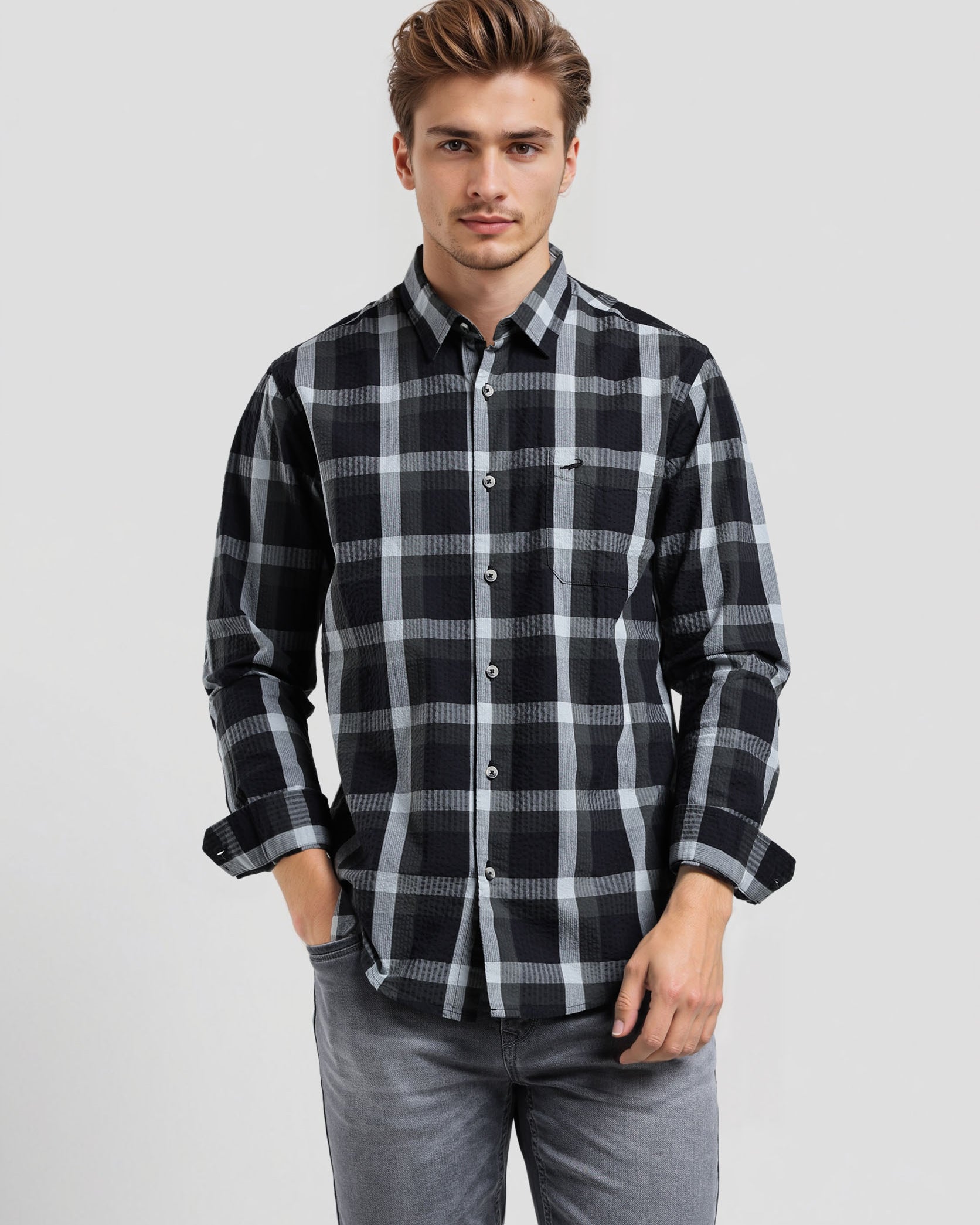 Man wearing a black and gray plaid shirt on a light gray background