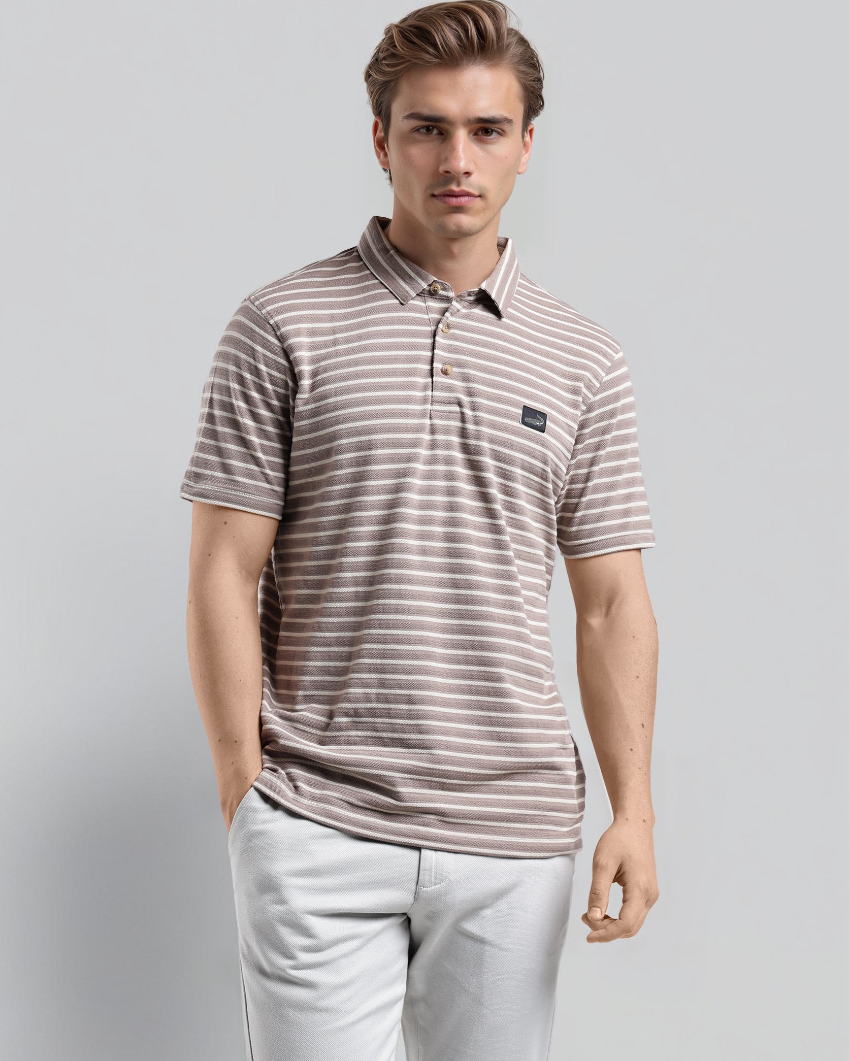 Man wearing a striped polo shirt and light pants on a gray background