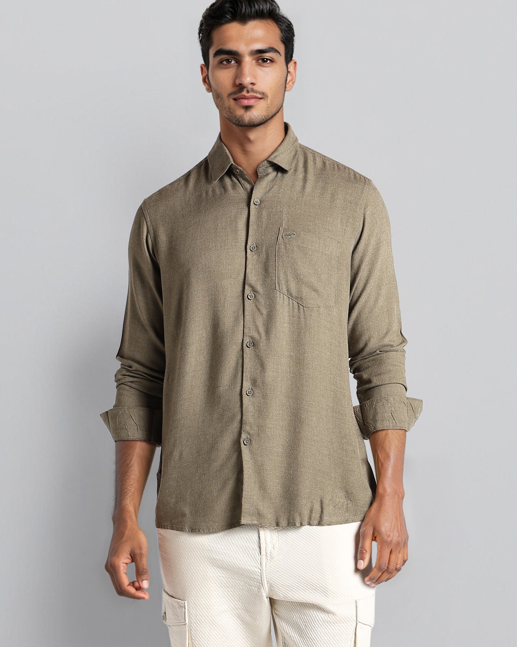 Man wearing a green shirt and white pants against a gray background