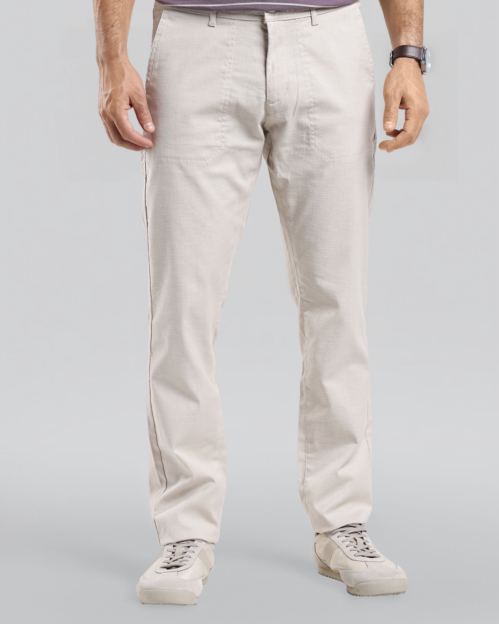 Person wearing light-colored pants and a striped shirt on a plain background