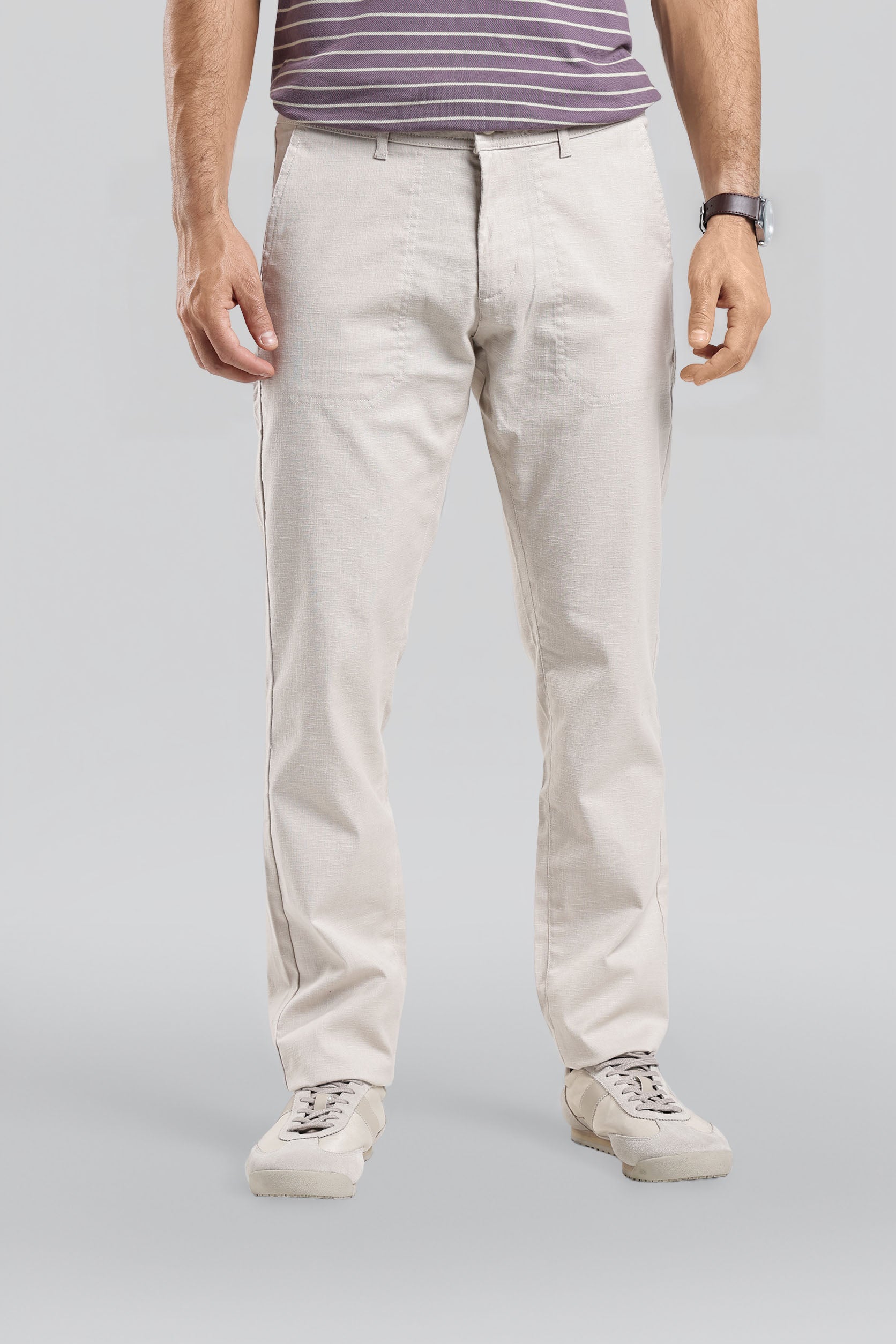 Person wearing light-colored pants and a striped shirt on a plain background