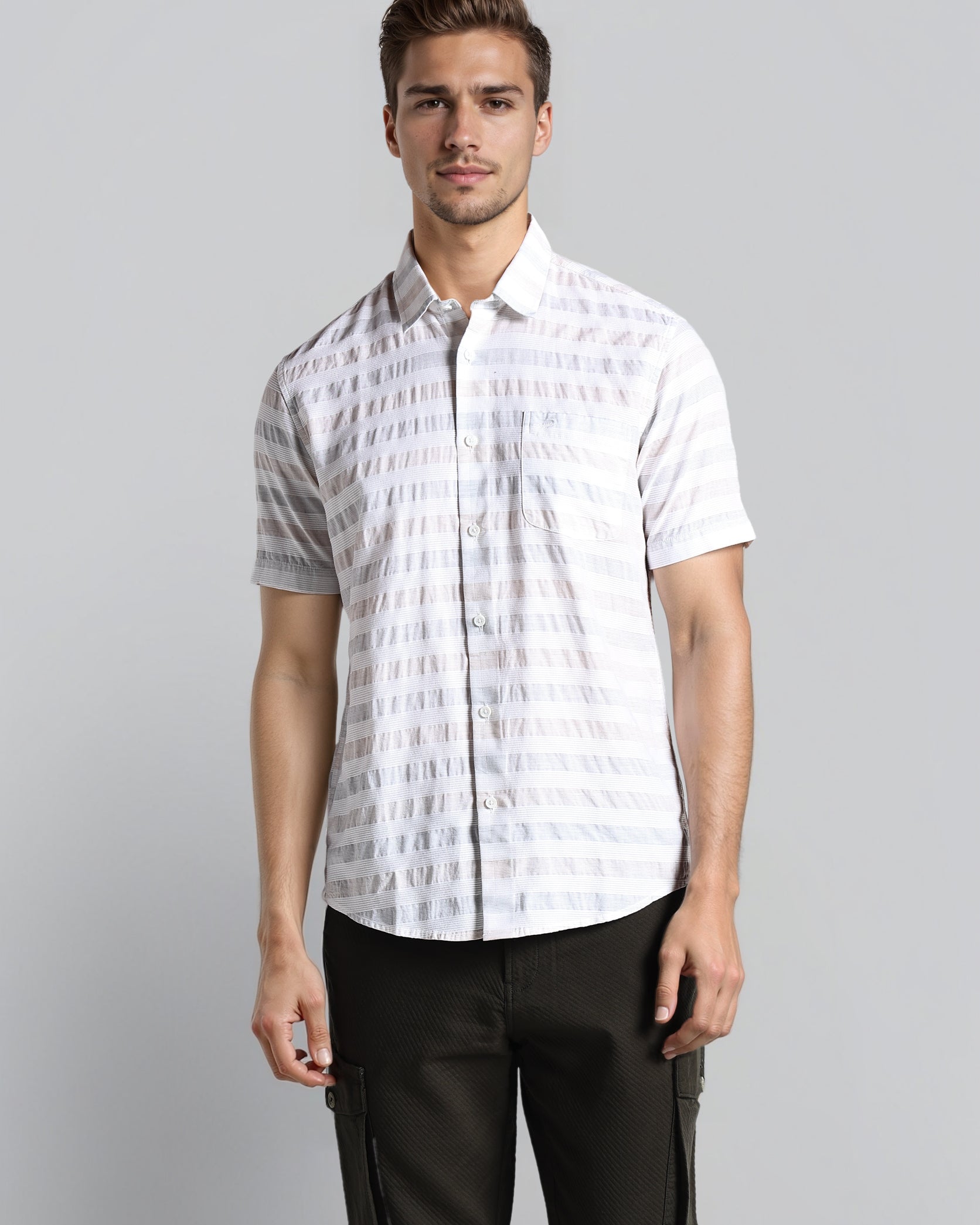 Man wearing a white patterned shirt and black pants on a gray background