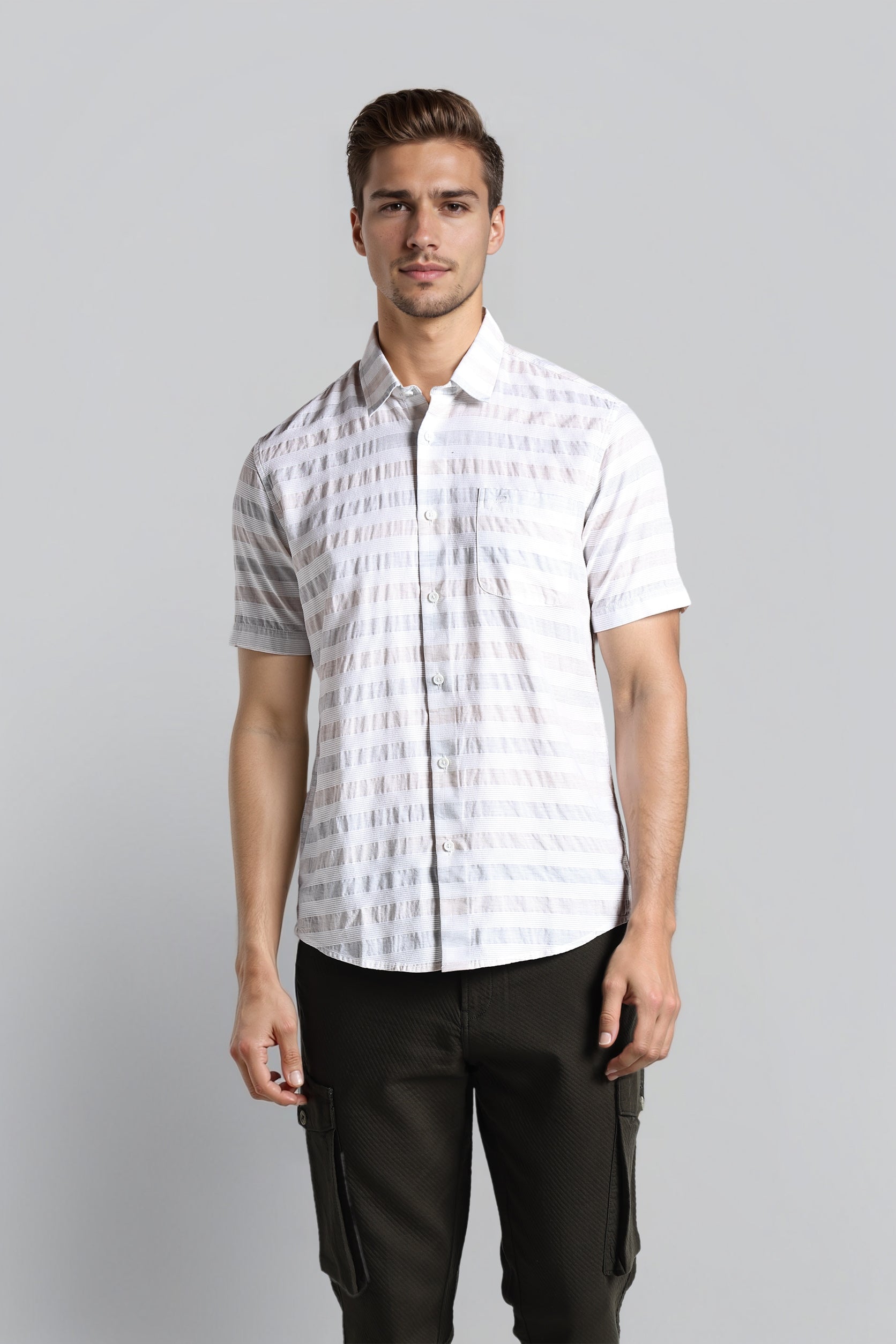 Man wearing a white patterned shirt and black pants on a gray background