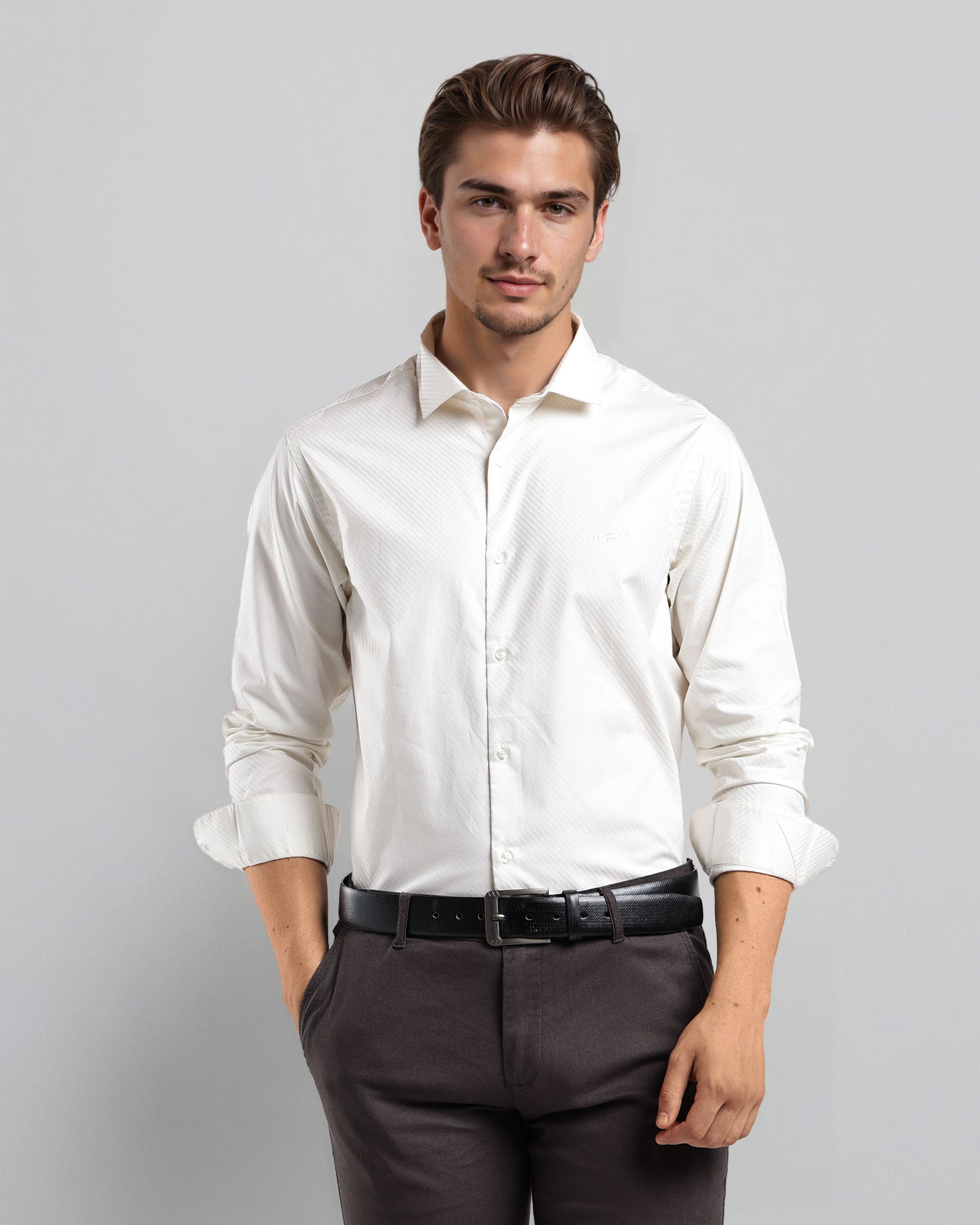 Man wearing a white dress shirt and dark pants against a gray background