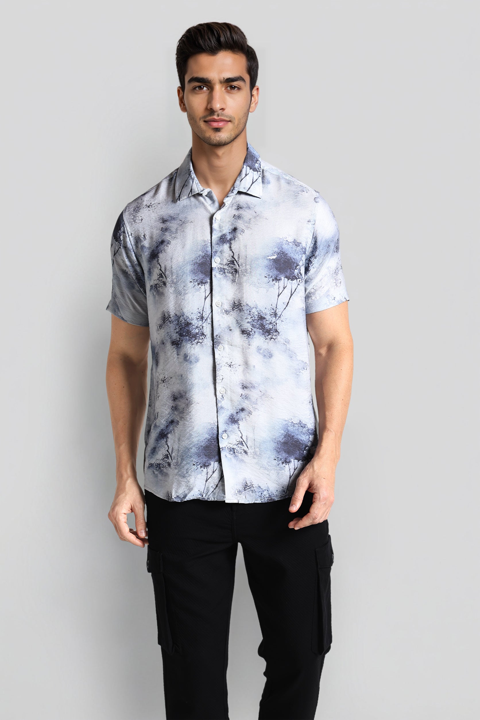 Man wearing a short-sleeve, patterned shirt with a plain background