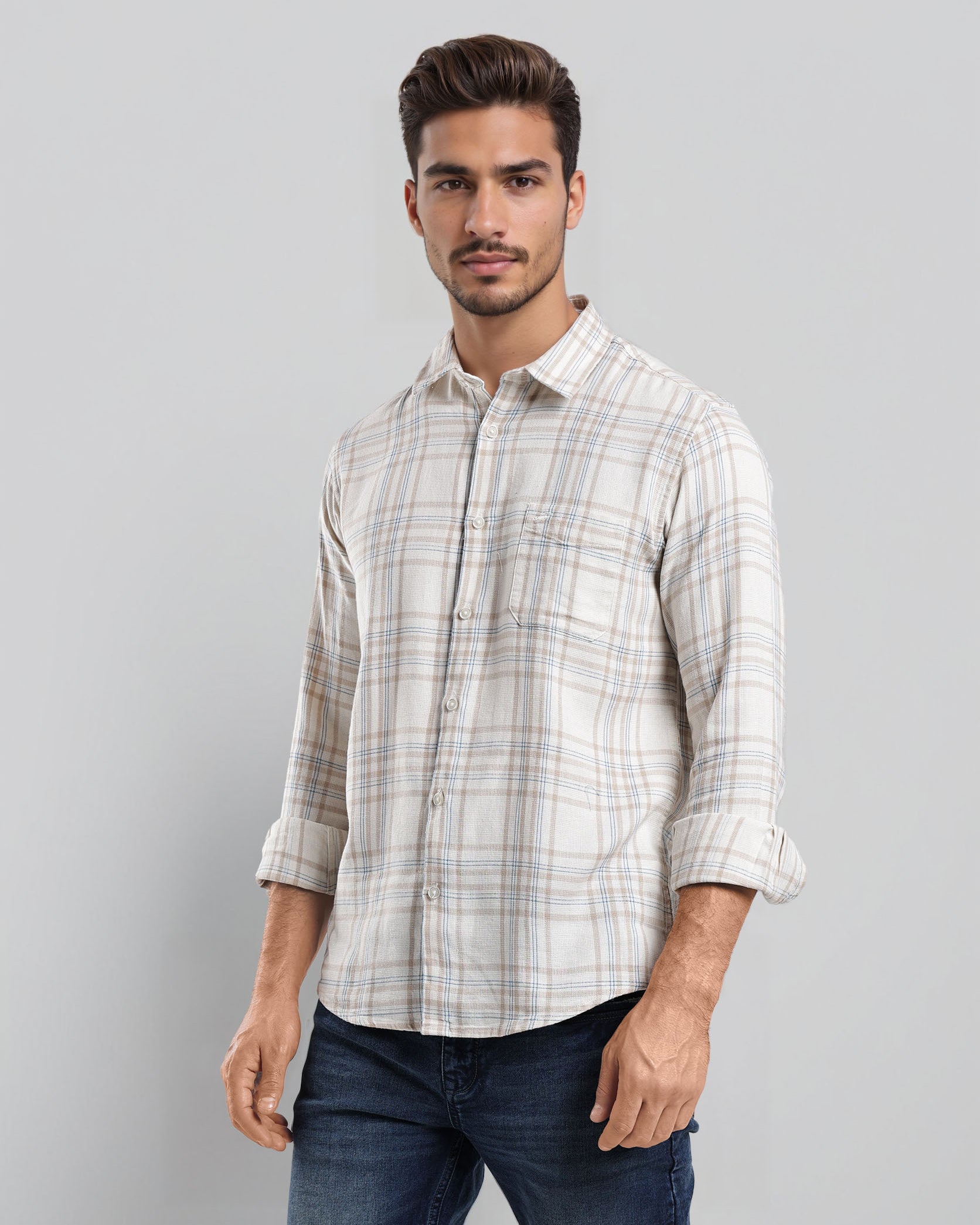 Man wearing a plaid shirt and jeans against a gray background