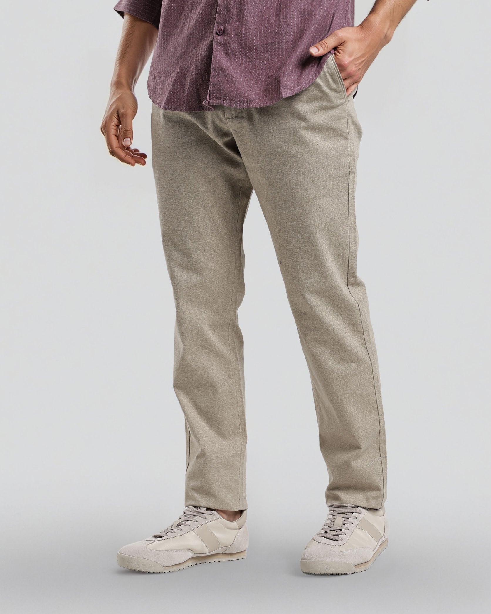 Person wearing a purple shirt and beige pants on a plain background