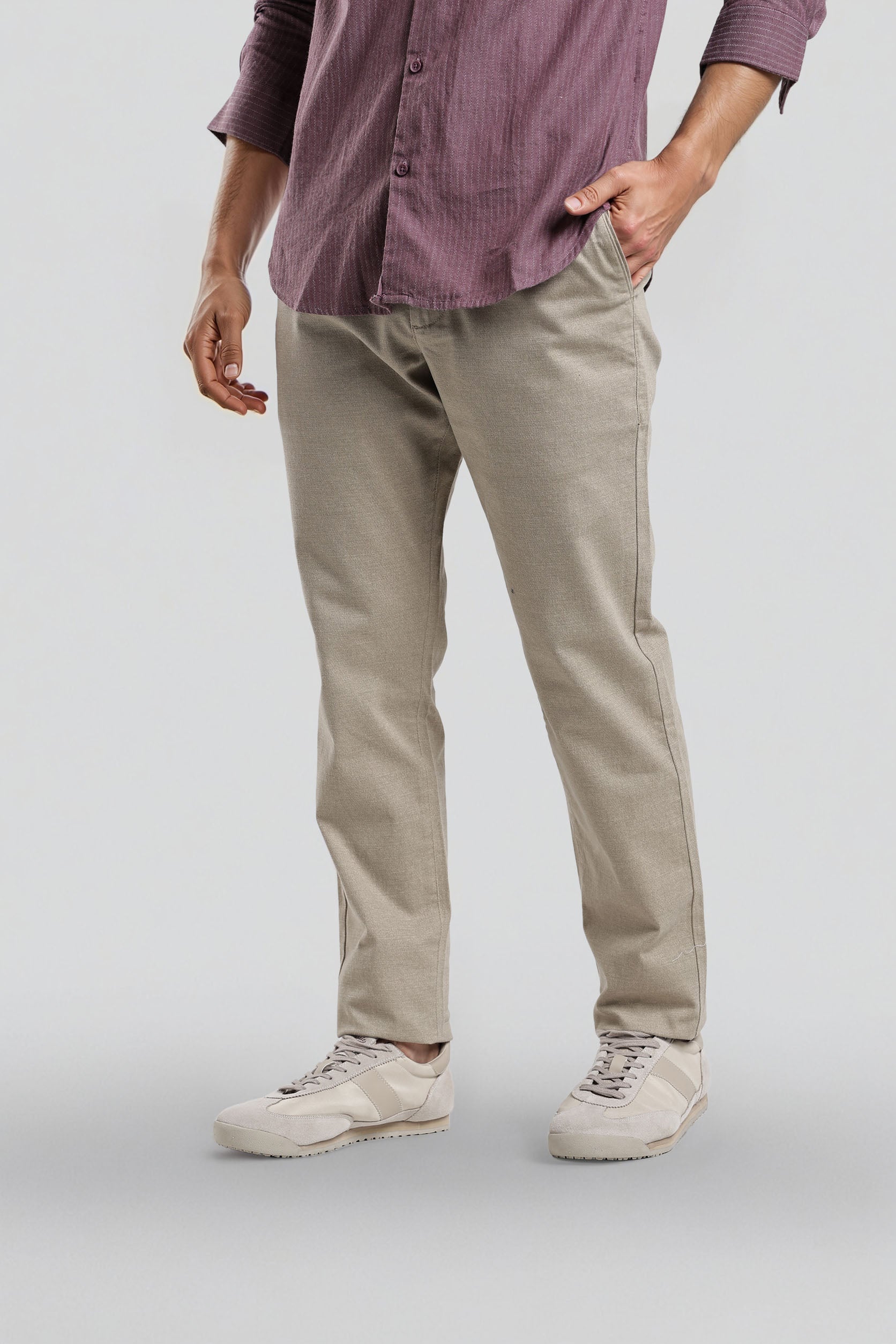 Person wearing a purple shirt and beige pants on a plain background