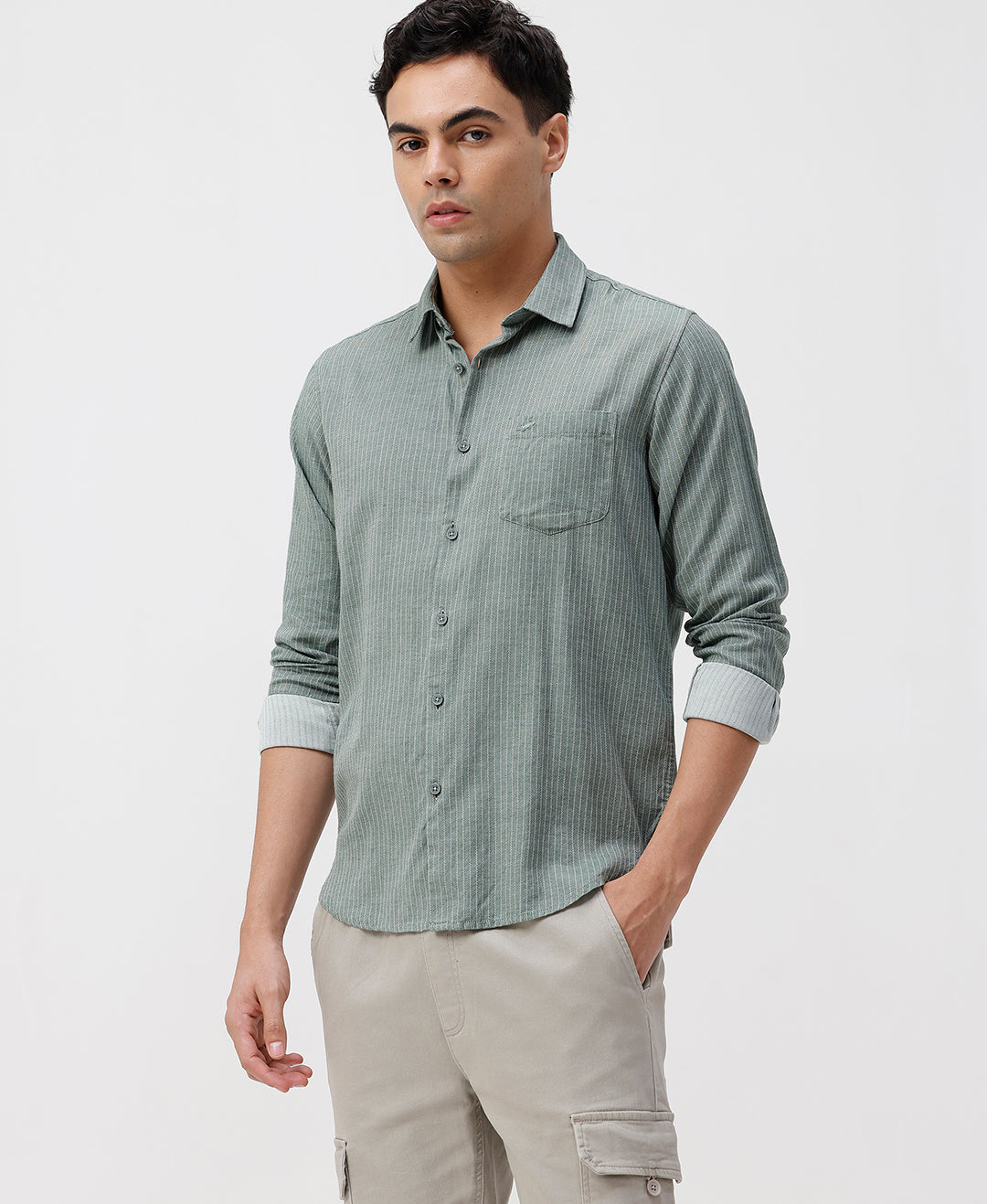 Man wearing a light green checkered shirt and beige pants on a white background