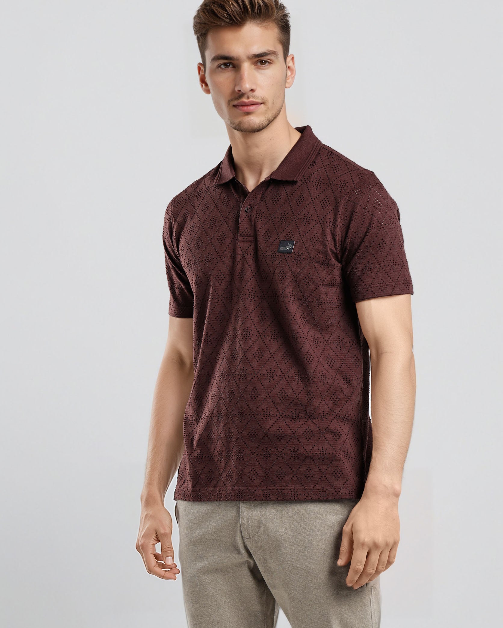 Man wearing a maroon polo shirt and beige pants on a light gray background