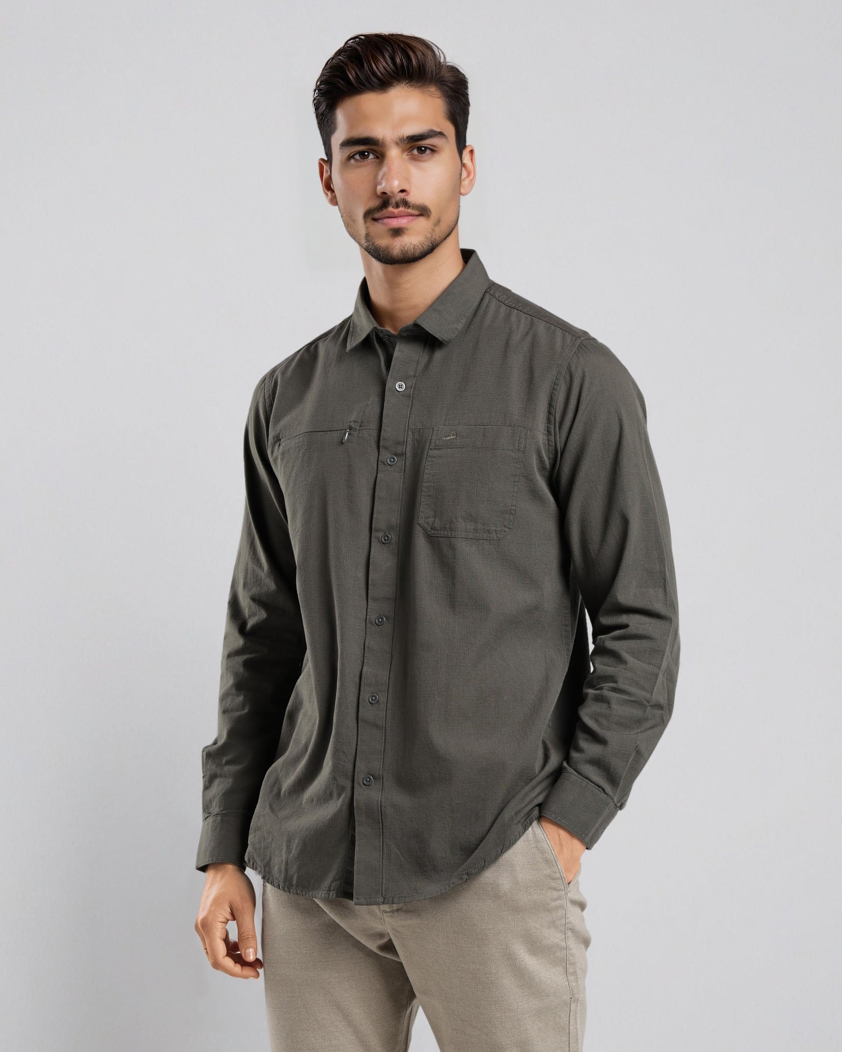 Man wearing a dark gray button-up shirt and beige pants on a light gray background