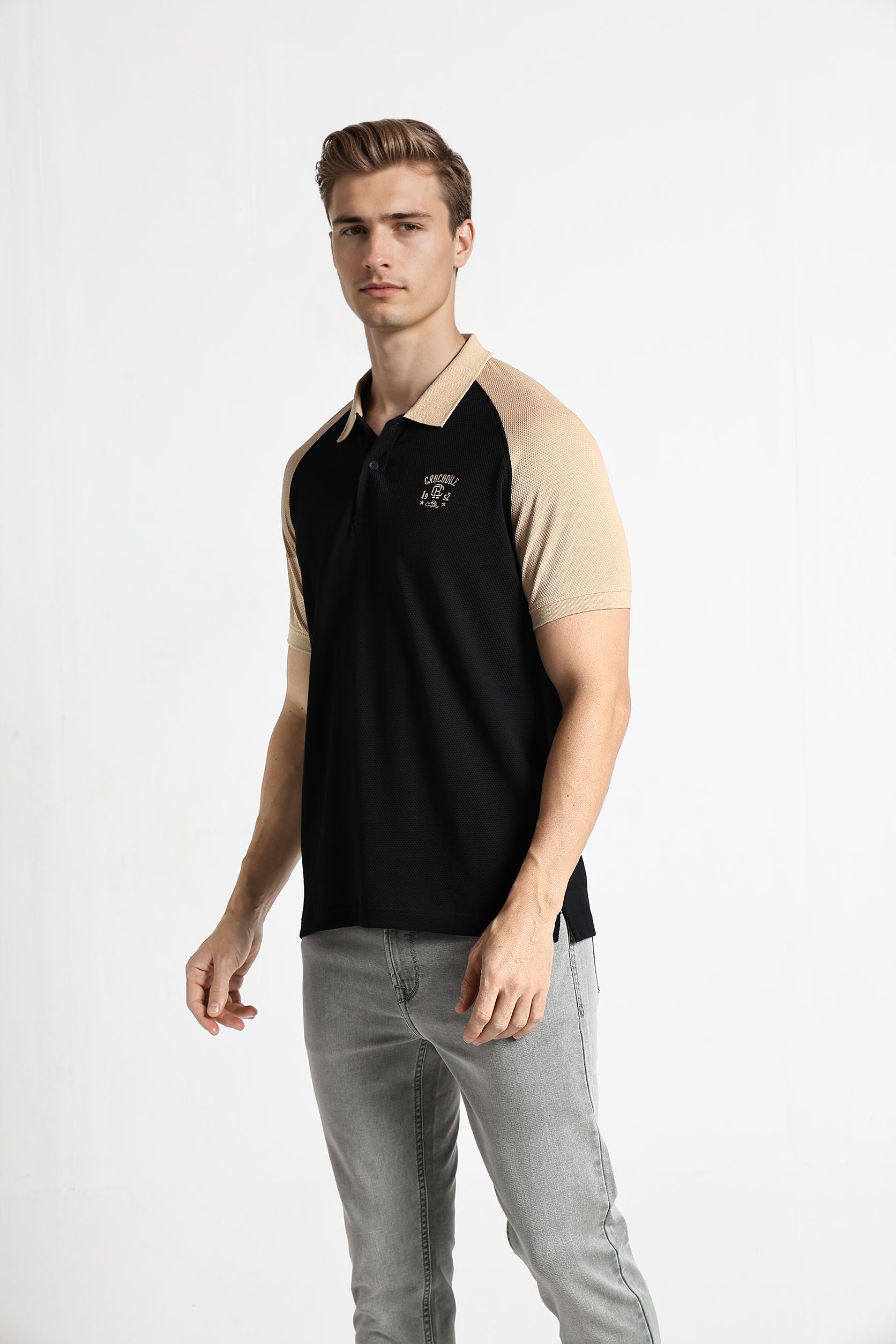 Man wearing a black and beige polo shirt on a white background