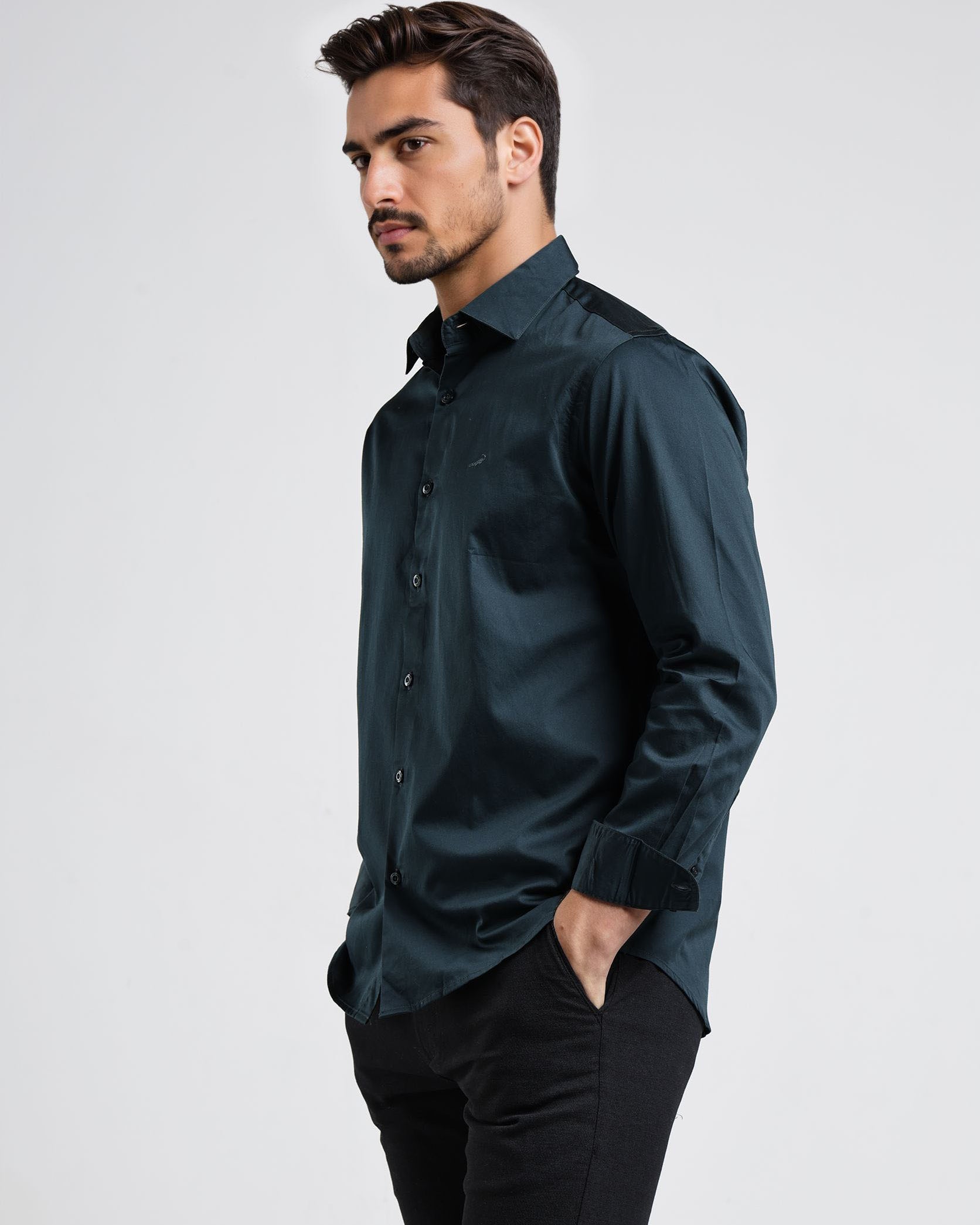 Man wearing a dark green shirt and black pants on a white background