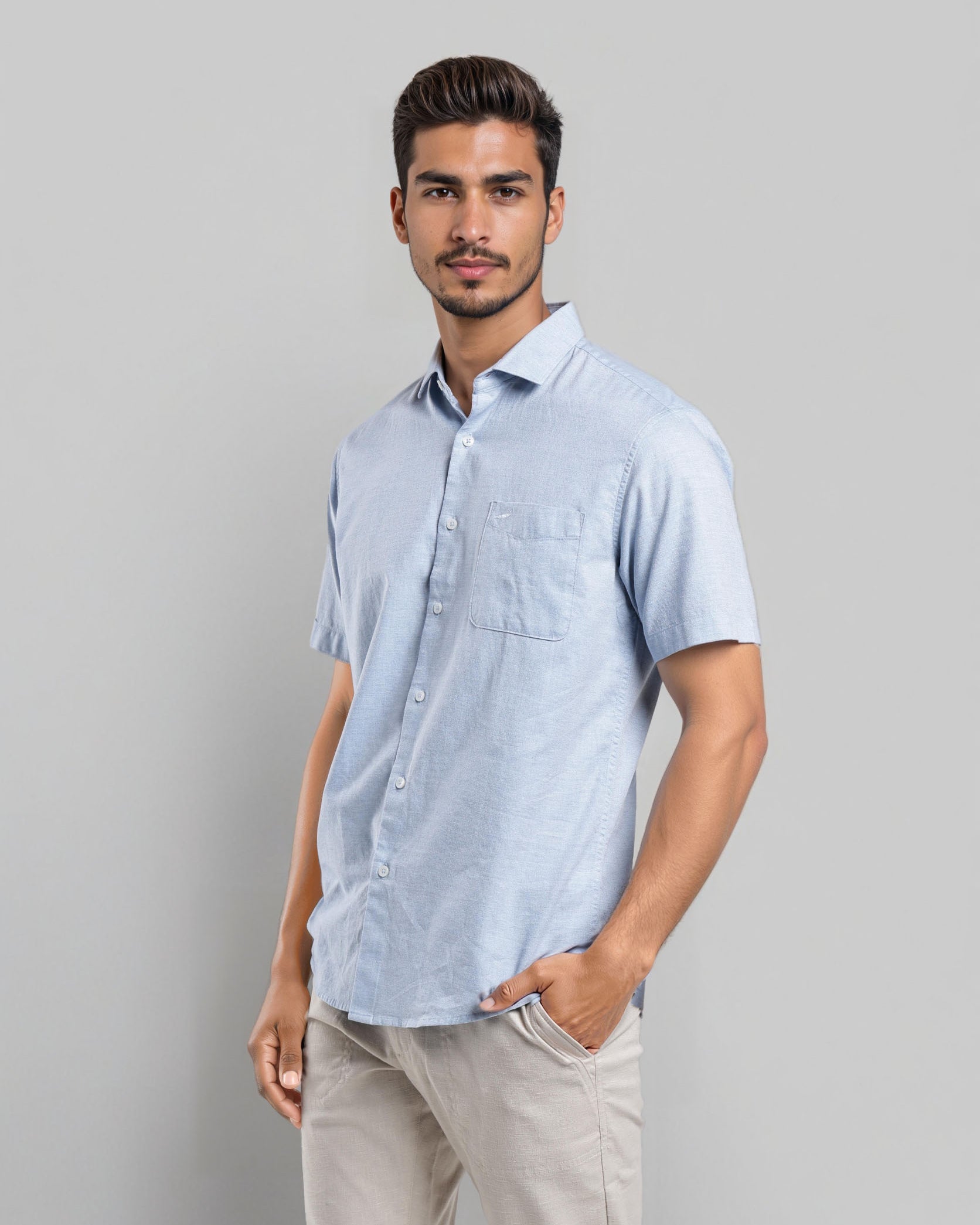 Man wearing a light blue short-sleeve shirt against a gray background