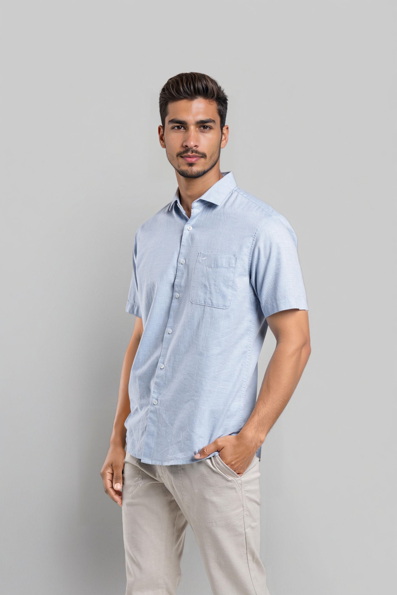 Man wearing a light blue short-sleeve shirt against a gray background