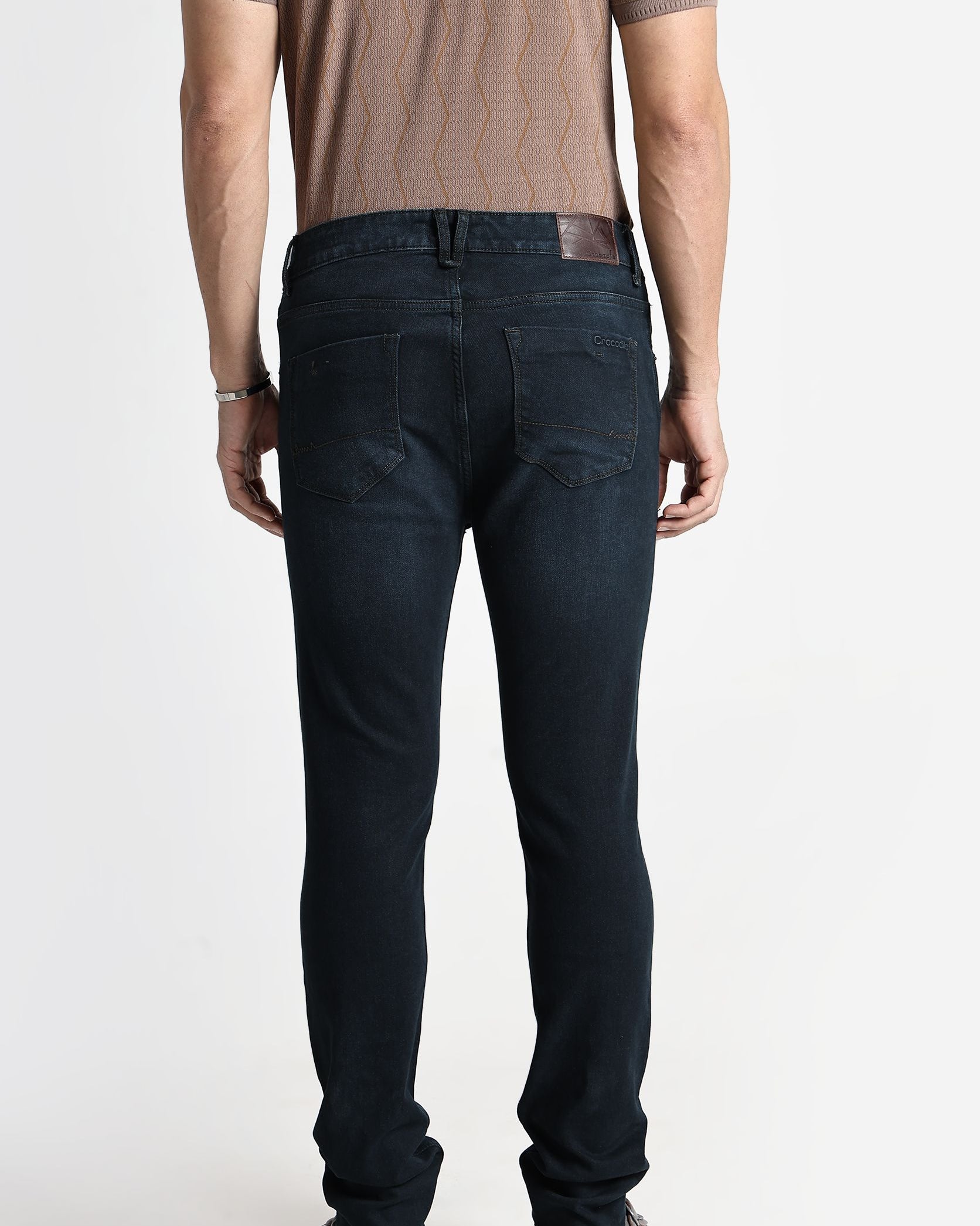 Person wearing dark jeans and a brown shirt on a white background