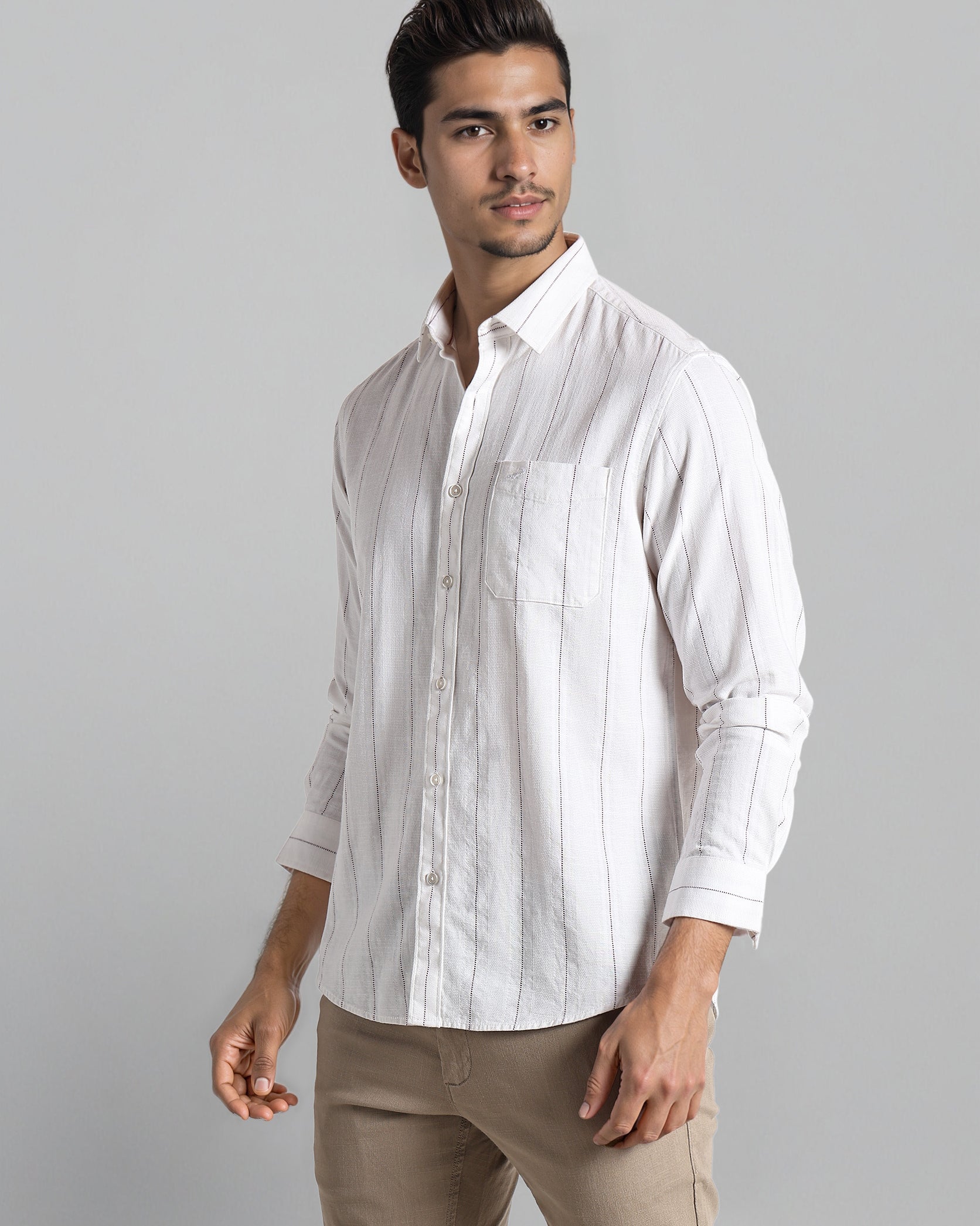 Man wearing a white striped shirt and beige pants on a gray background