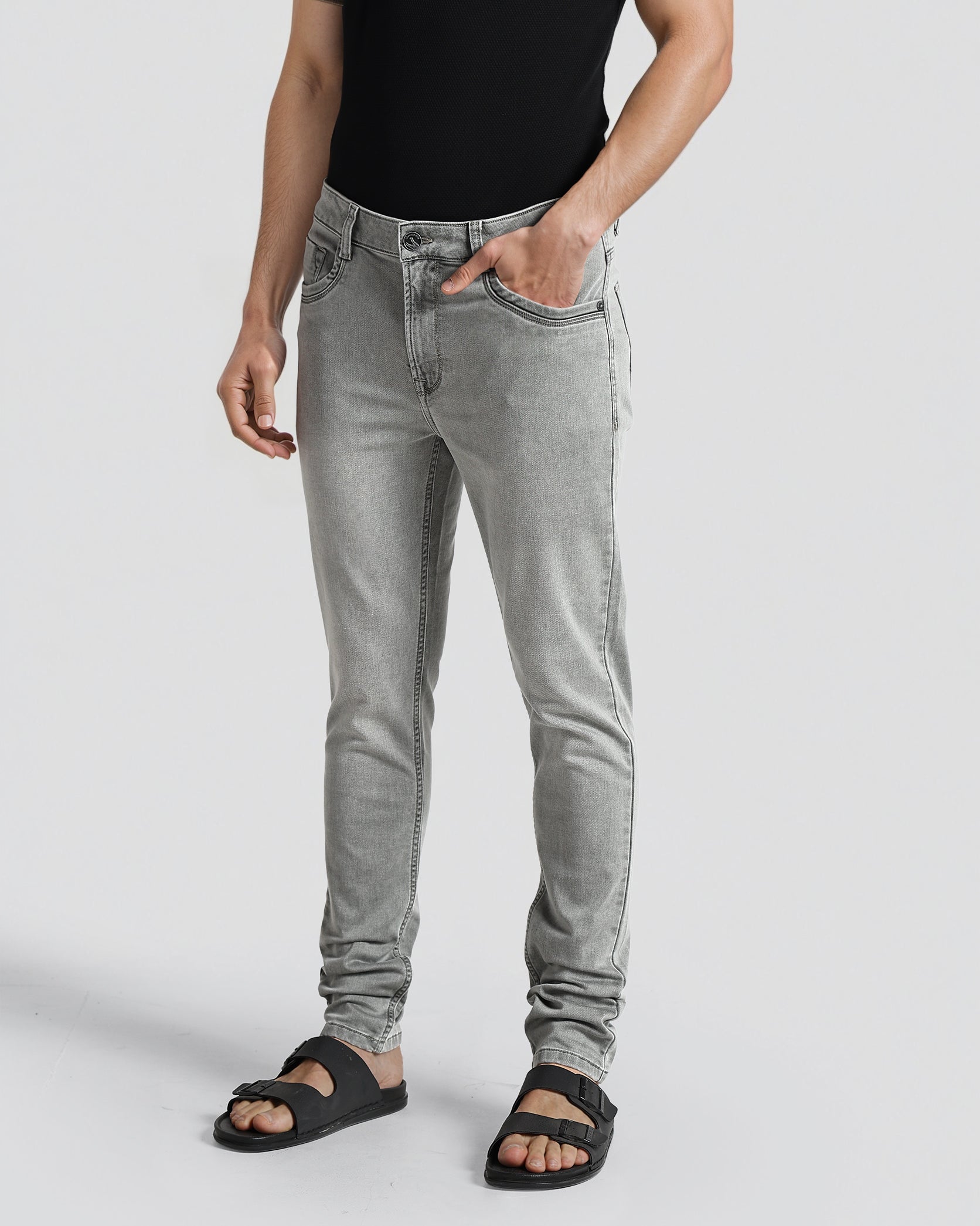Person wearing gray jeans and black sandals on a light gray background
