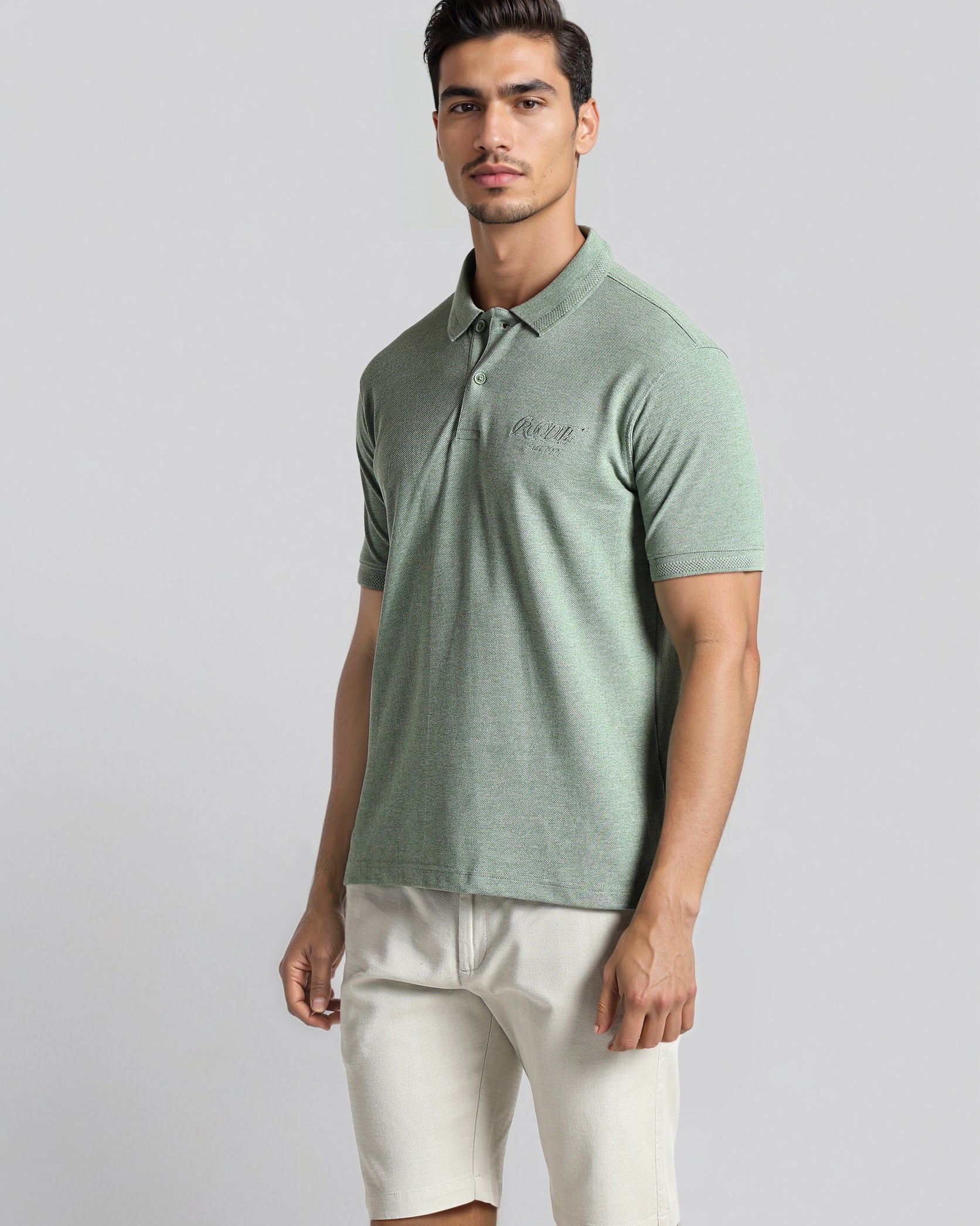 Man wearing a green polo shirt and white shorts on a gray background