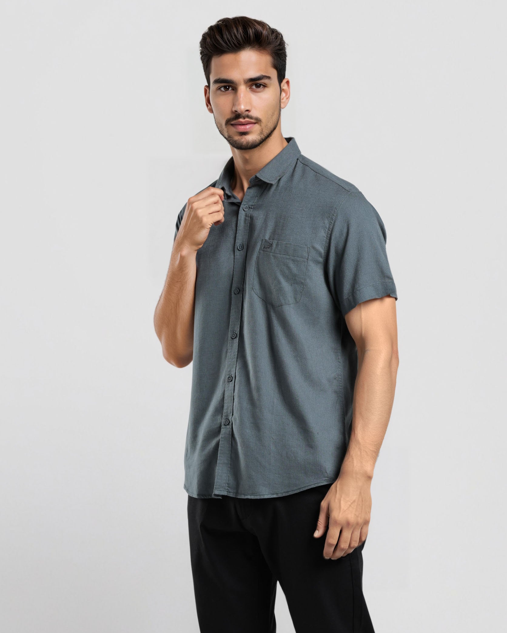 Man wearing a gray short-sleeve shirt and black pants on a light gray background