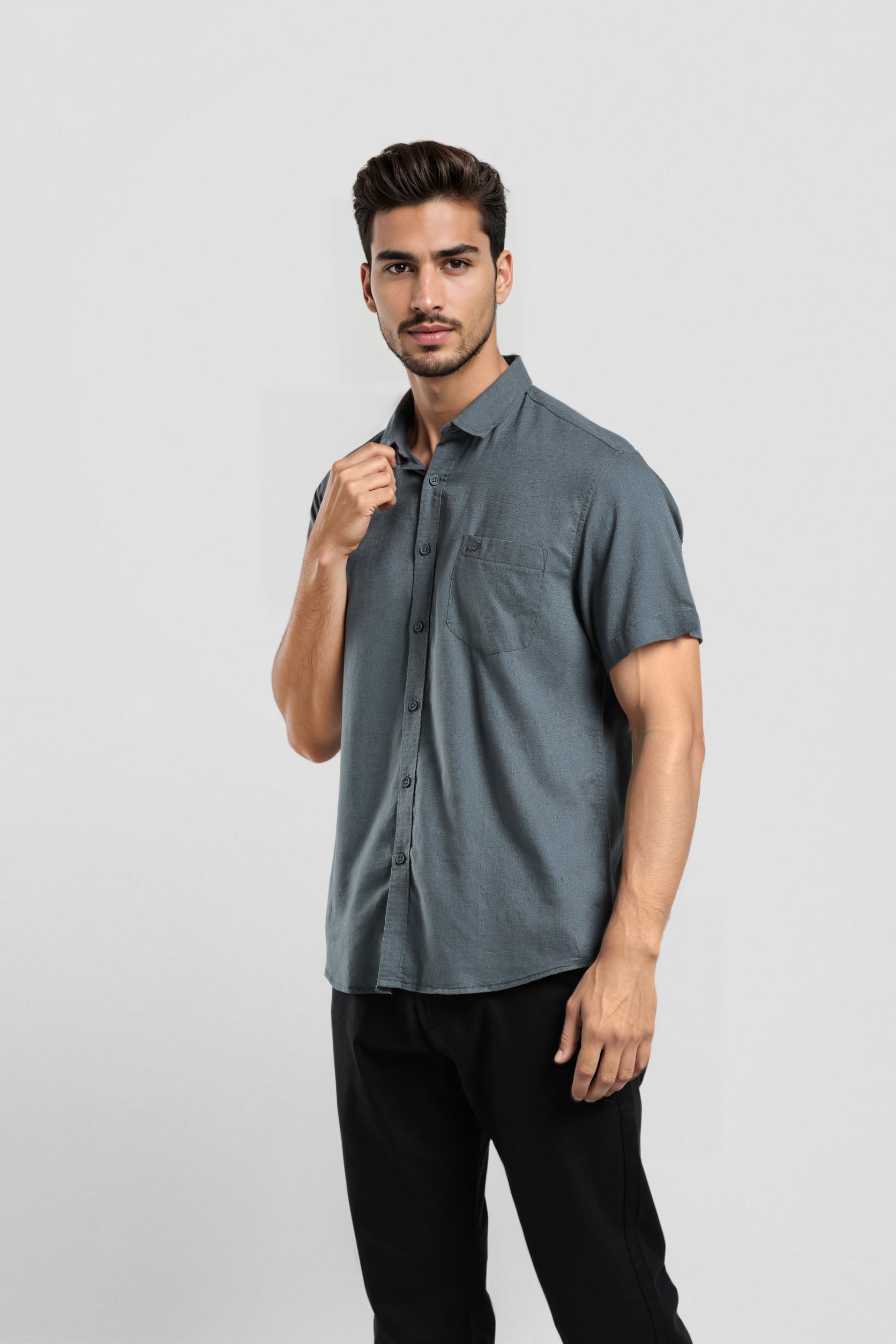 Man wearing a gray short-sleeve shirt and black pants on a light gray background