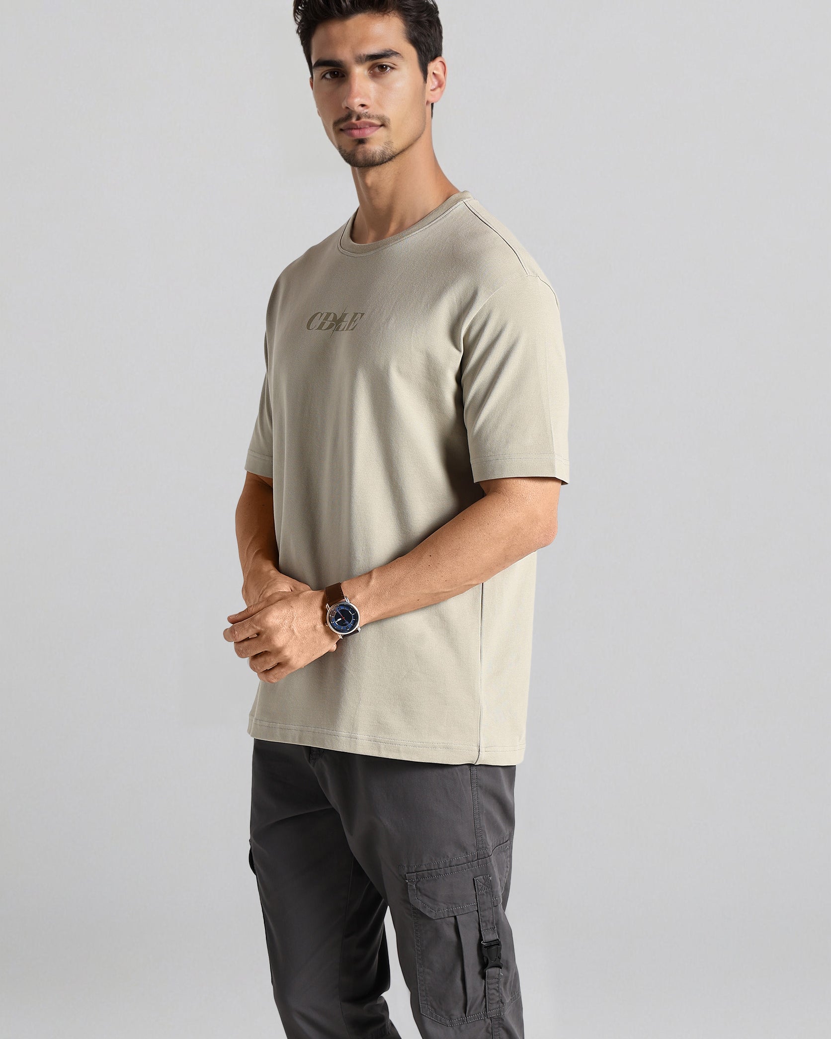 Man wearing a beige t-shirt and gray cargo pants on a light gray background