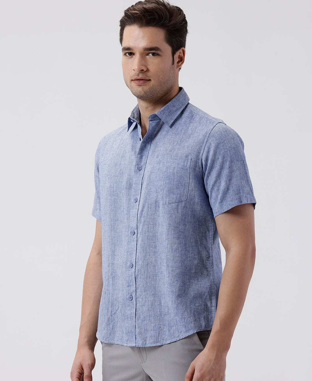 Man wearing a blue premium tensil linen shirt blue on a light gray background