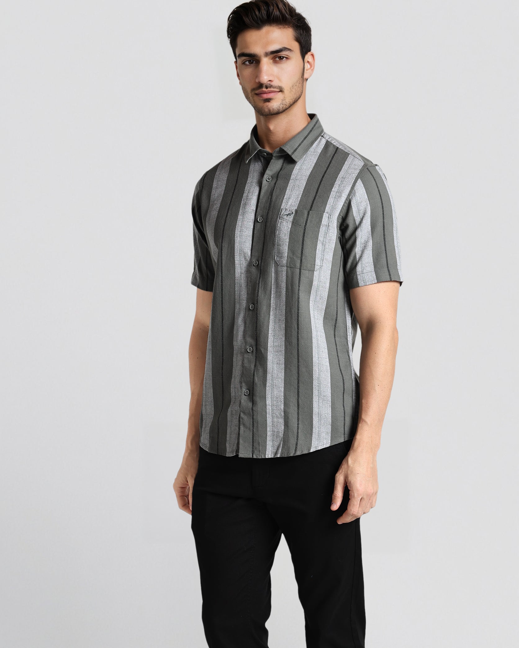 Man wearing a striped shirt and black pants on a light gray background