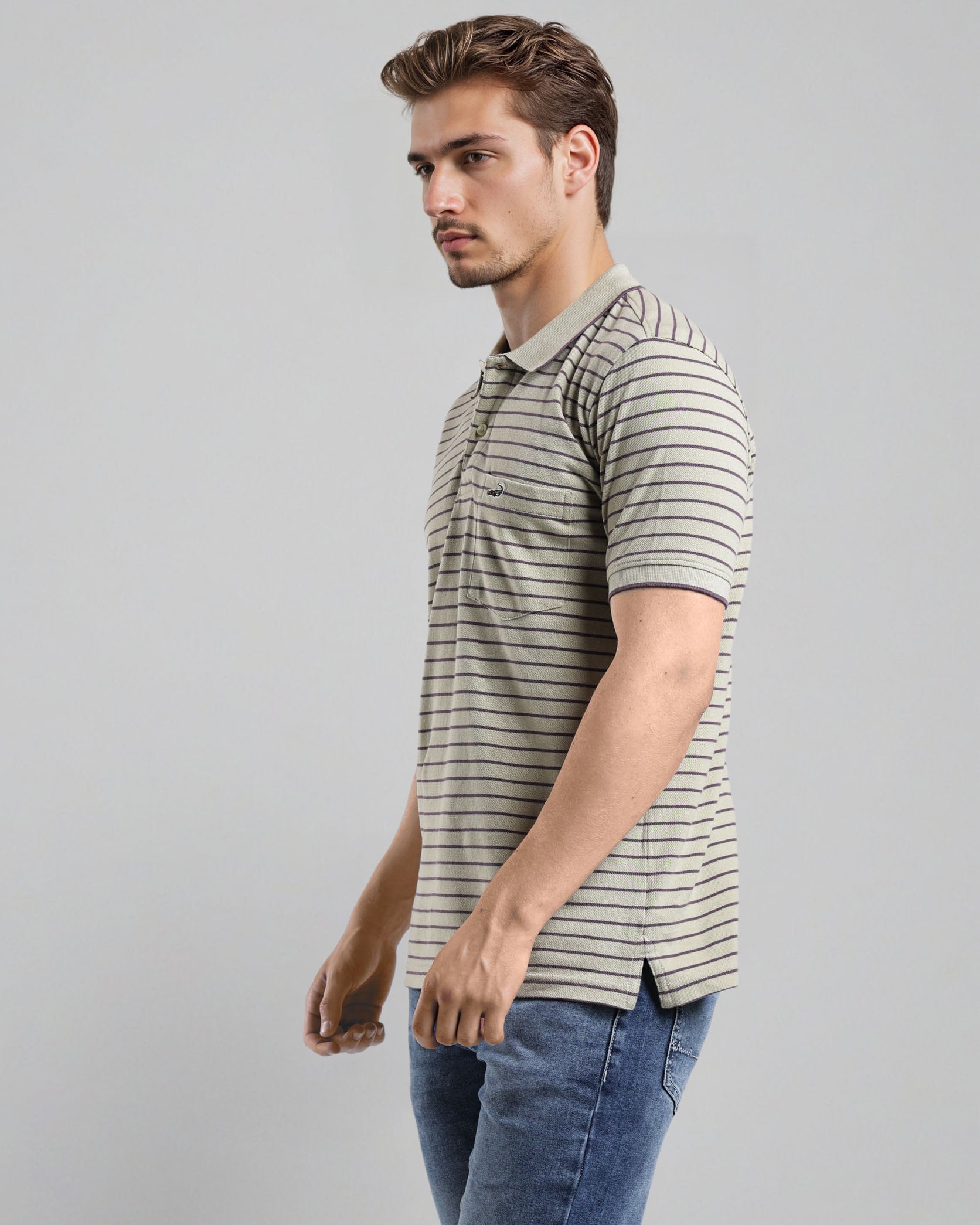 Man wearing a striped polo shirt and jeans on a gray background